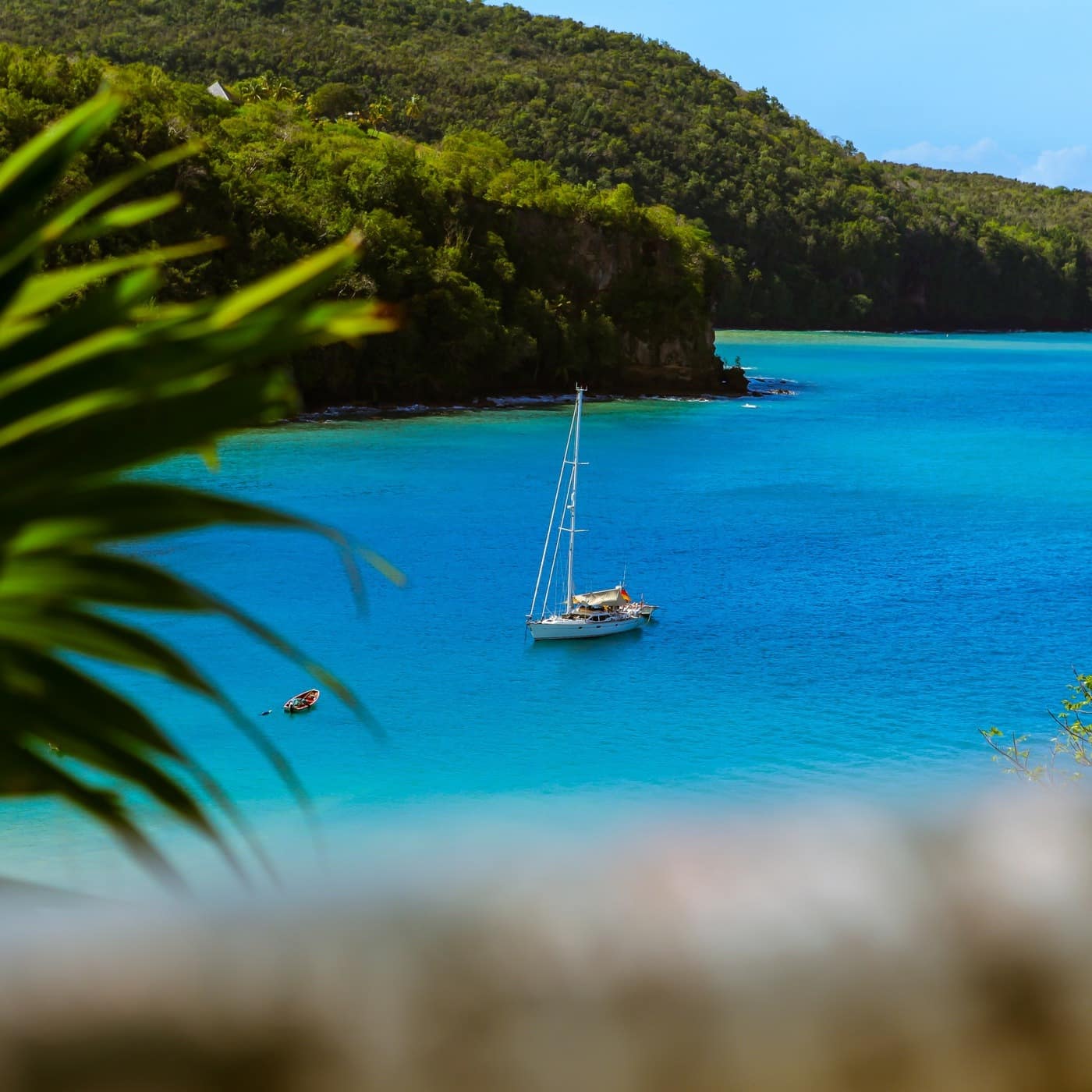 A single-hulled yacht sits in an empty bay of blue water in St Lucia