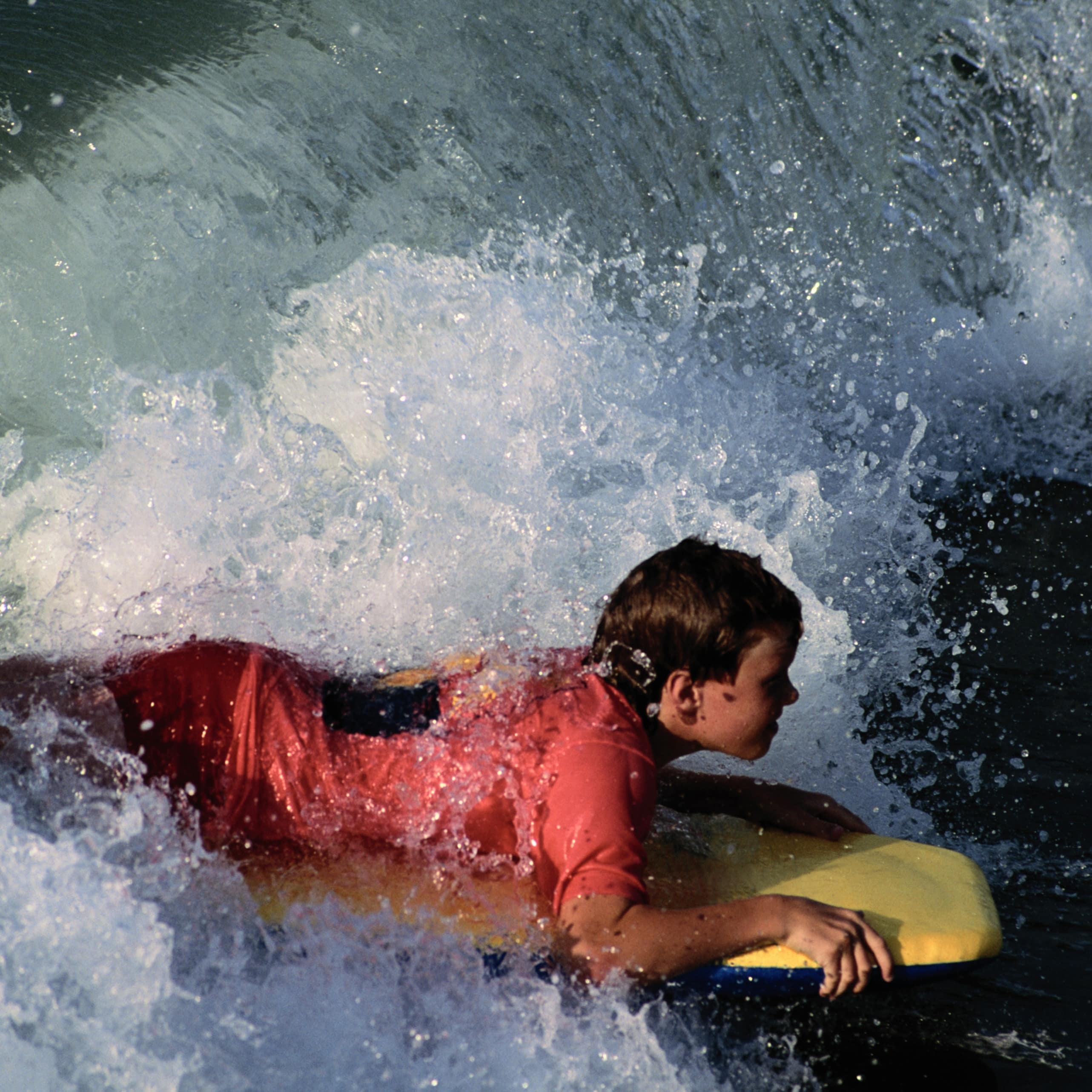 Dreng på bodyboard rider på en stor bølge
