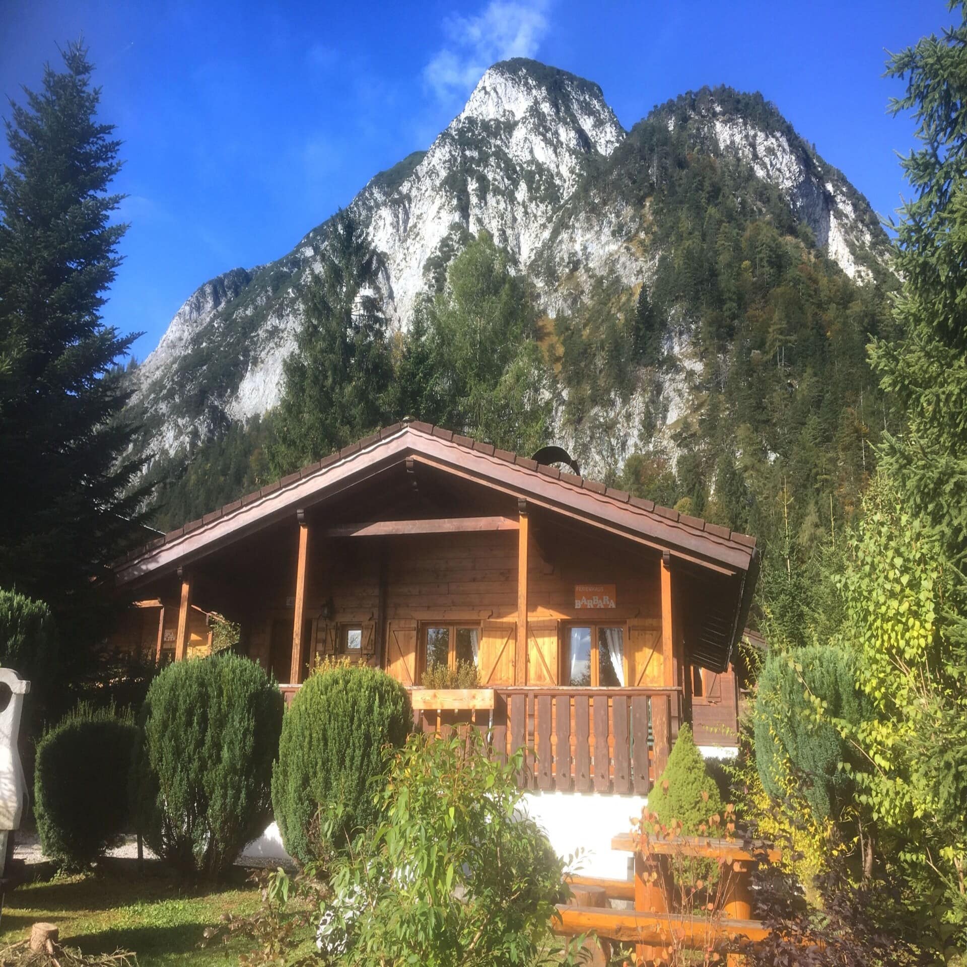 Eine Holzhütte mit Garten, dahinter ein Berg.