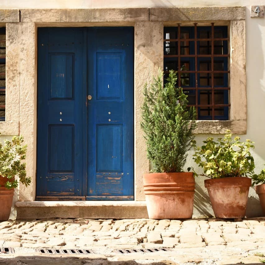 Natursandstein und Terrakotta-Töpfen verleihen diesem Ferienhaus in Kroatien mit blauer Haustüre mediterranes Flair 