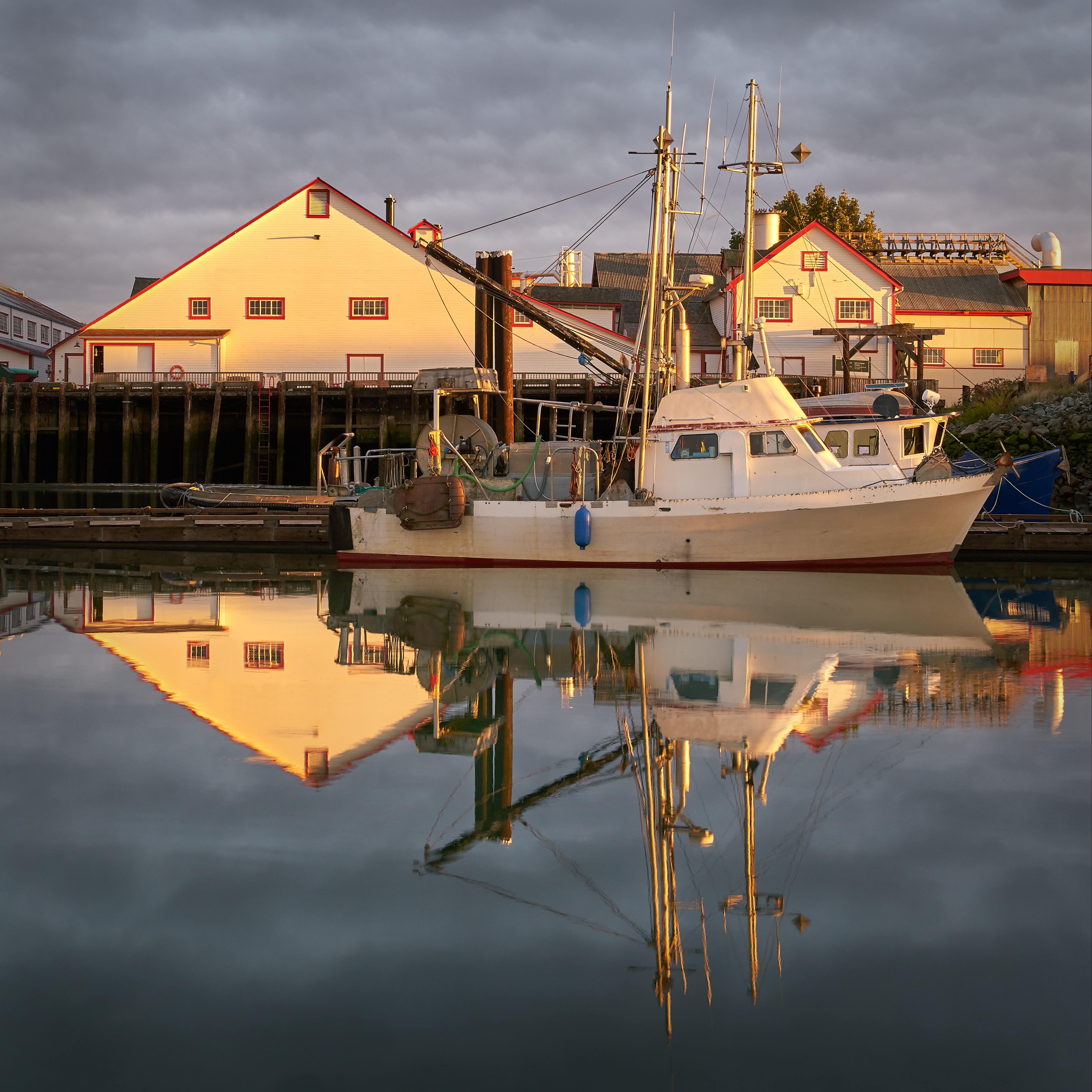 First light on the Gulf of Georgia Cannery Historic site in Steveston, British Columbia with reflection of boat and buildings