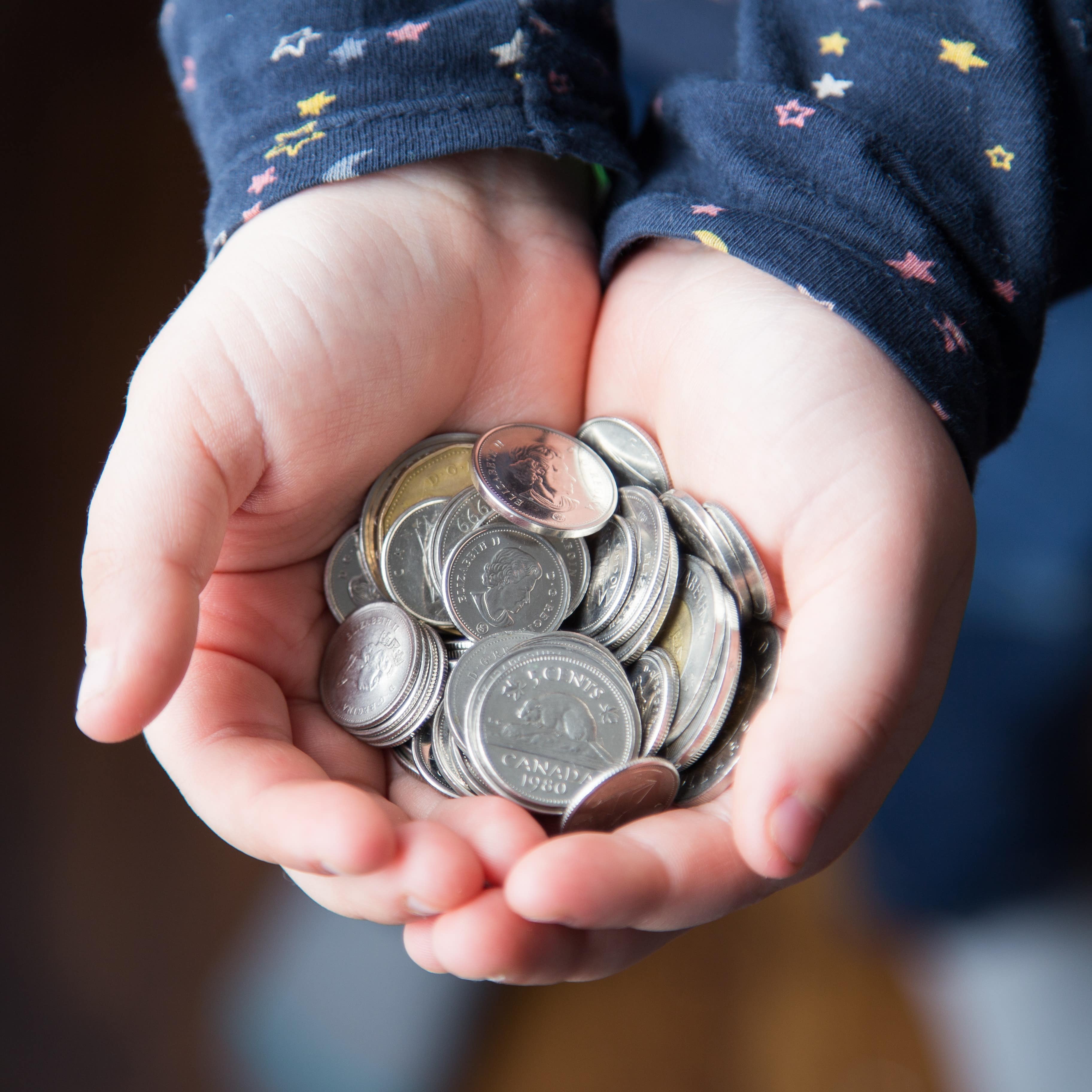 Child’s hands holding Canadian coins