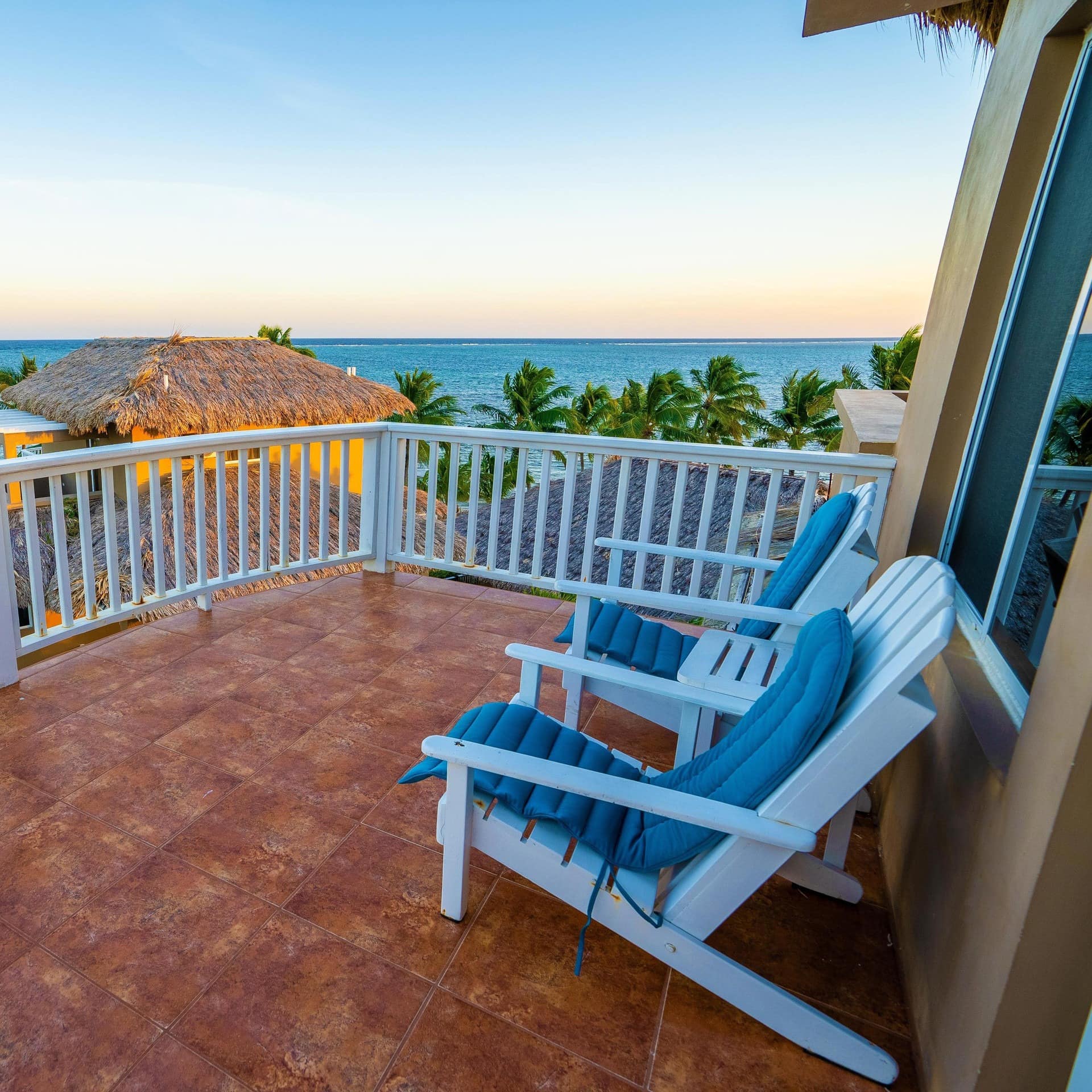 Oceanfront penthouse balcony overlooking the ocean and palm trees.