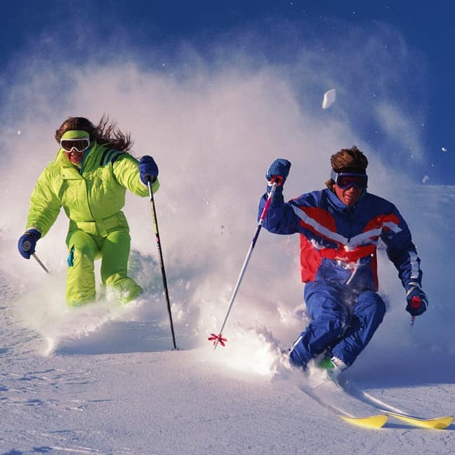 Couple skiing down snow-covered slope
