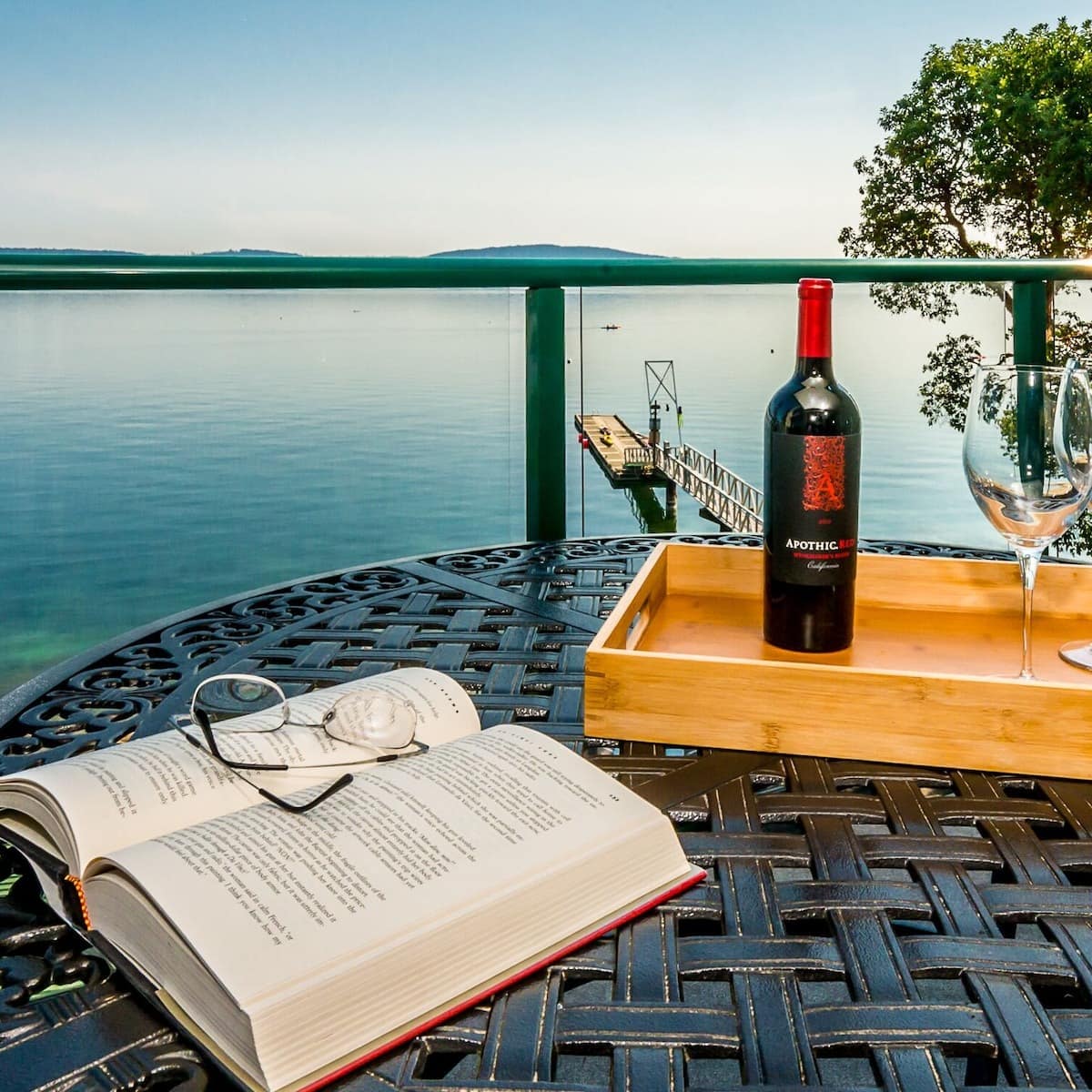 View of the blue waters in Vancouver from a holiday home with a book and wine on a table in the foreground