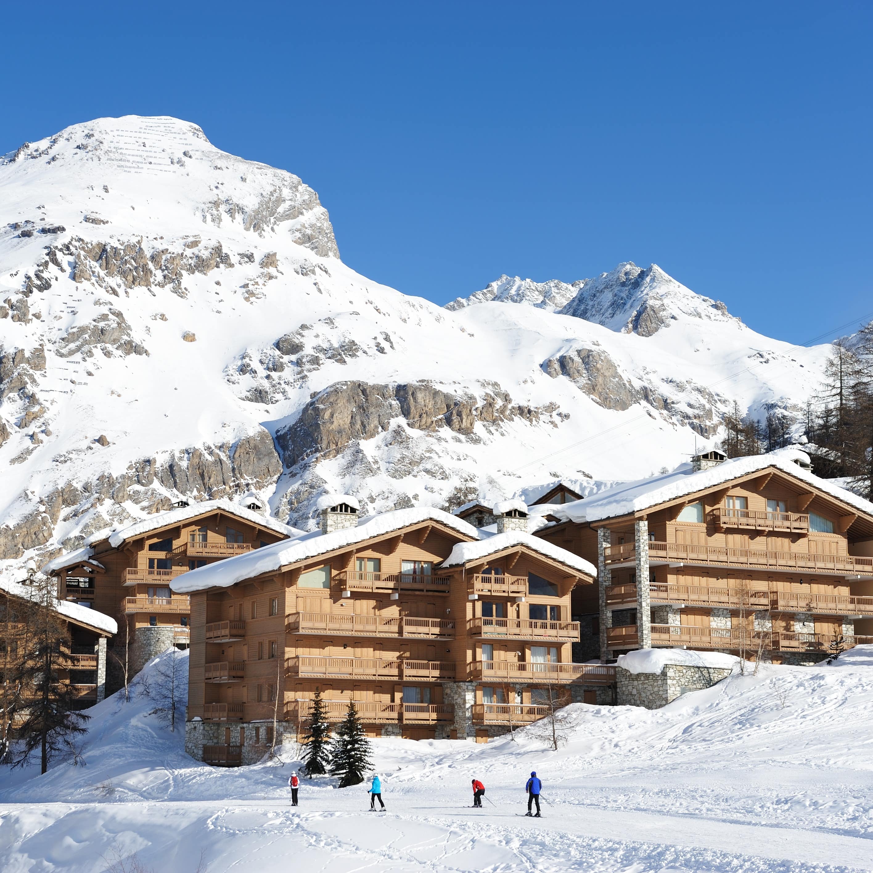 Ski resort against a snowy mountain backdrop on a clear sunny day