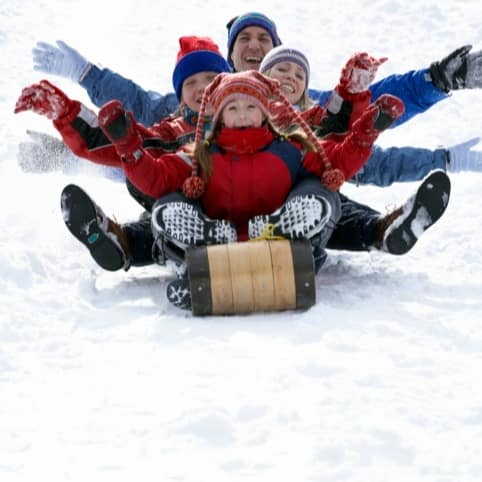 Family of 4 sledding down a hill on 1 sled
