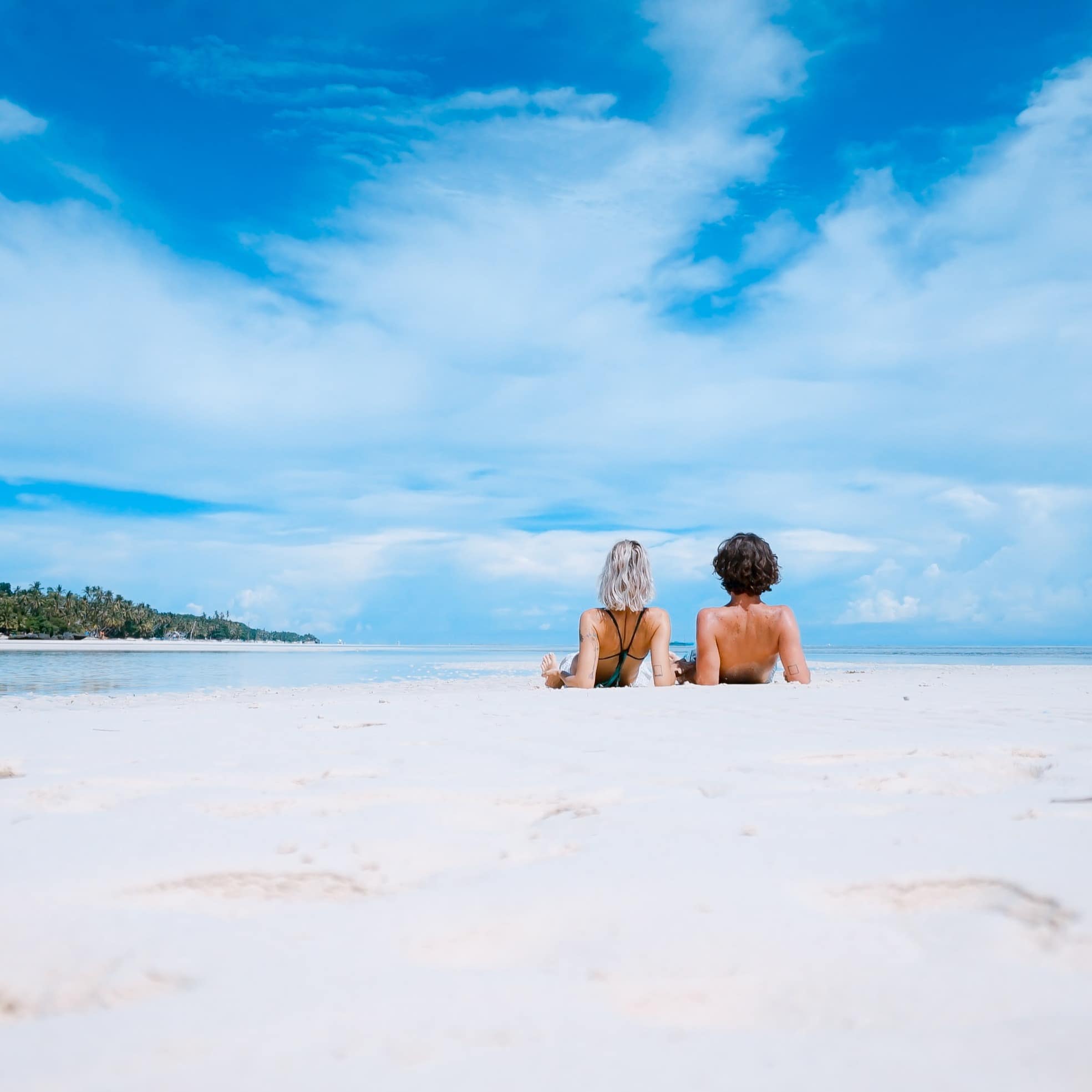 Two people laying on the white beaches of Hawaii