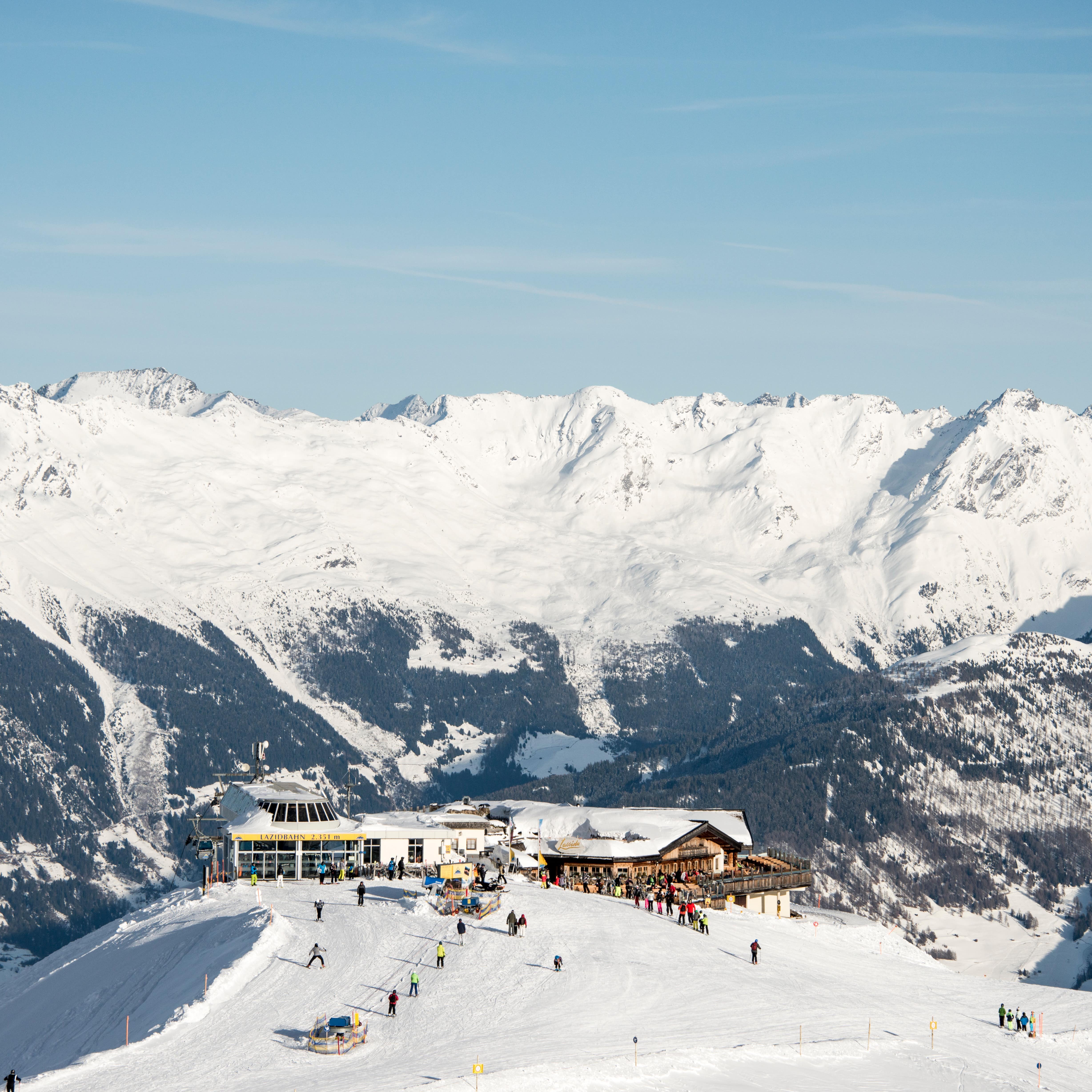 Ski resort on top of a hill surrounded by a range of snow-covered mountains