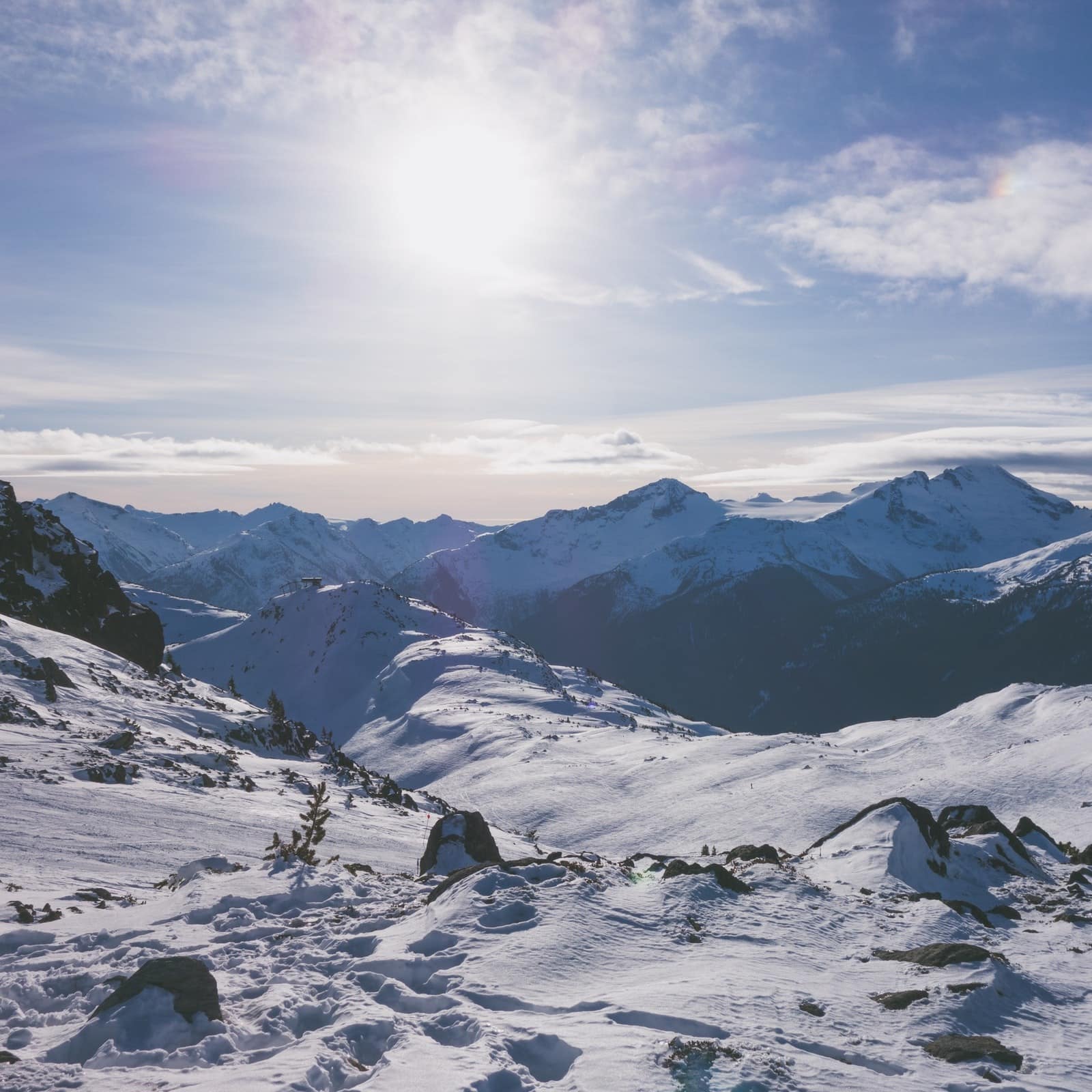 Skiers crossing a snowy mountain range under a bright sun