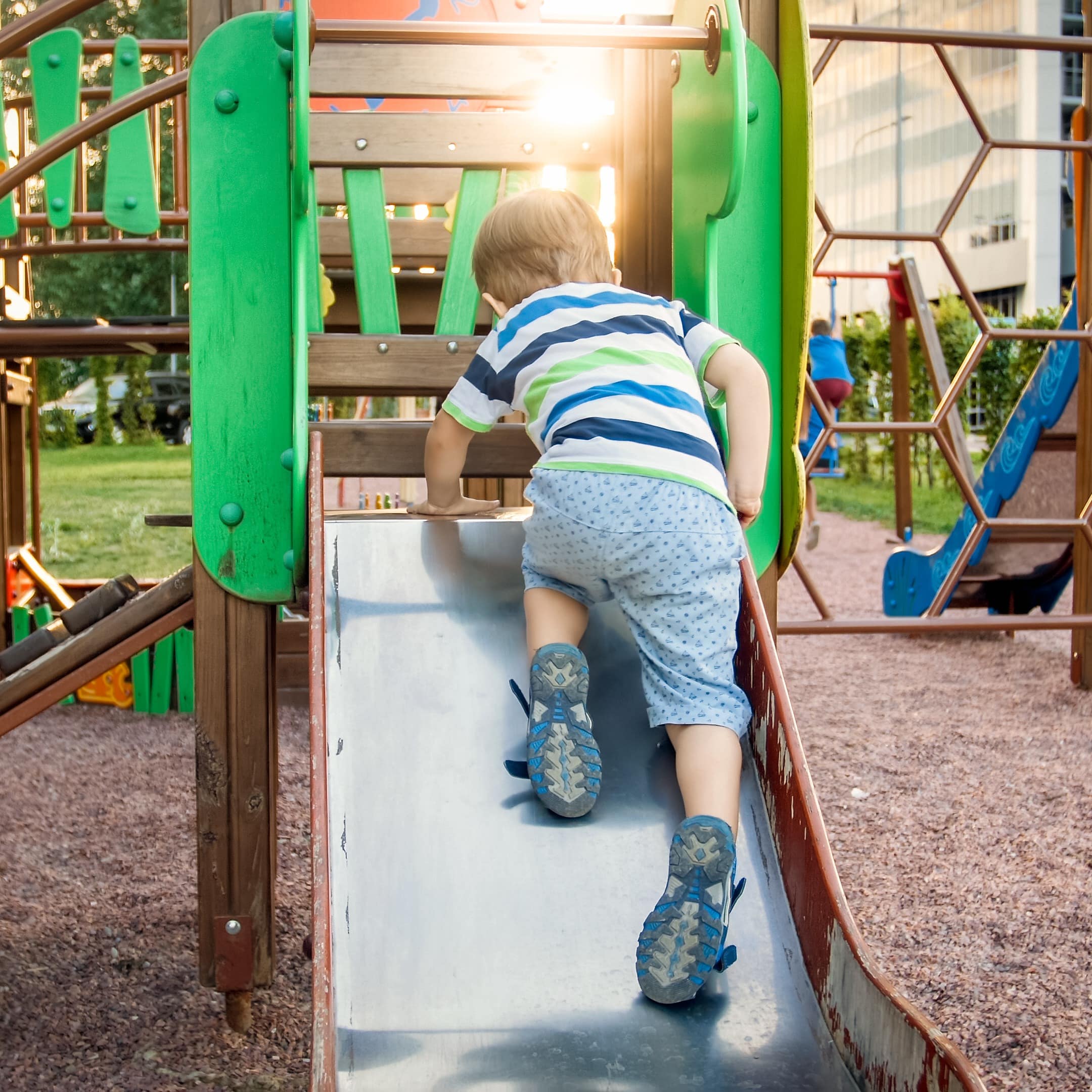 Toddler climbing up a slide at the playground