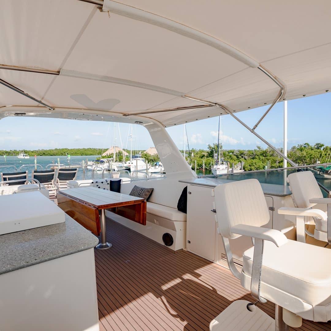Open area on the top deck of the luxury boat with a view of the sea, trees, and sailboats 