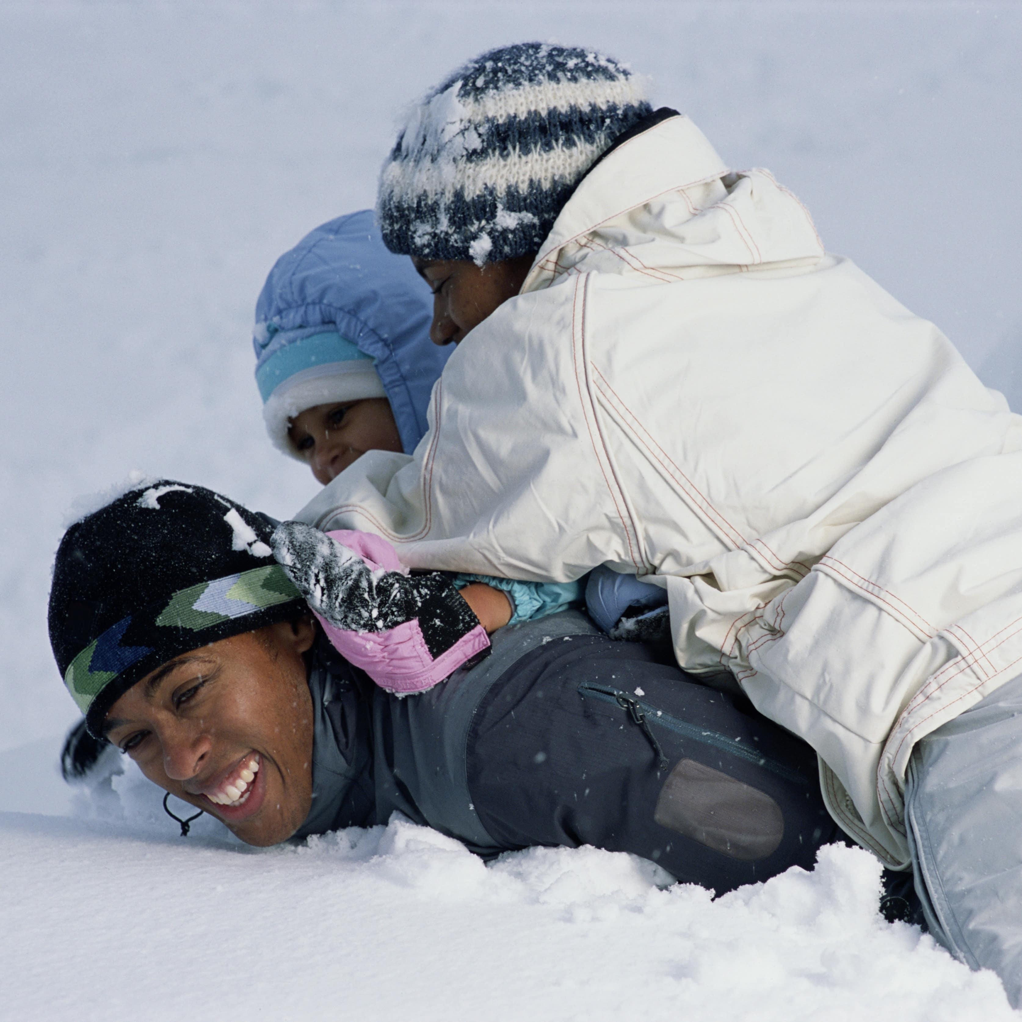 A mom playing in the snow with her children.