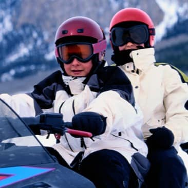 Child snowmobiling with a parent