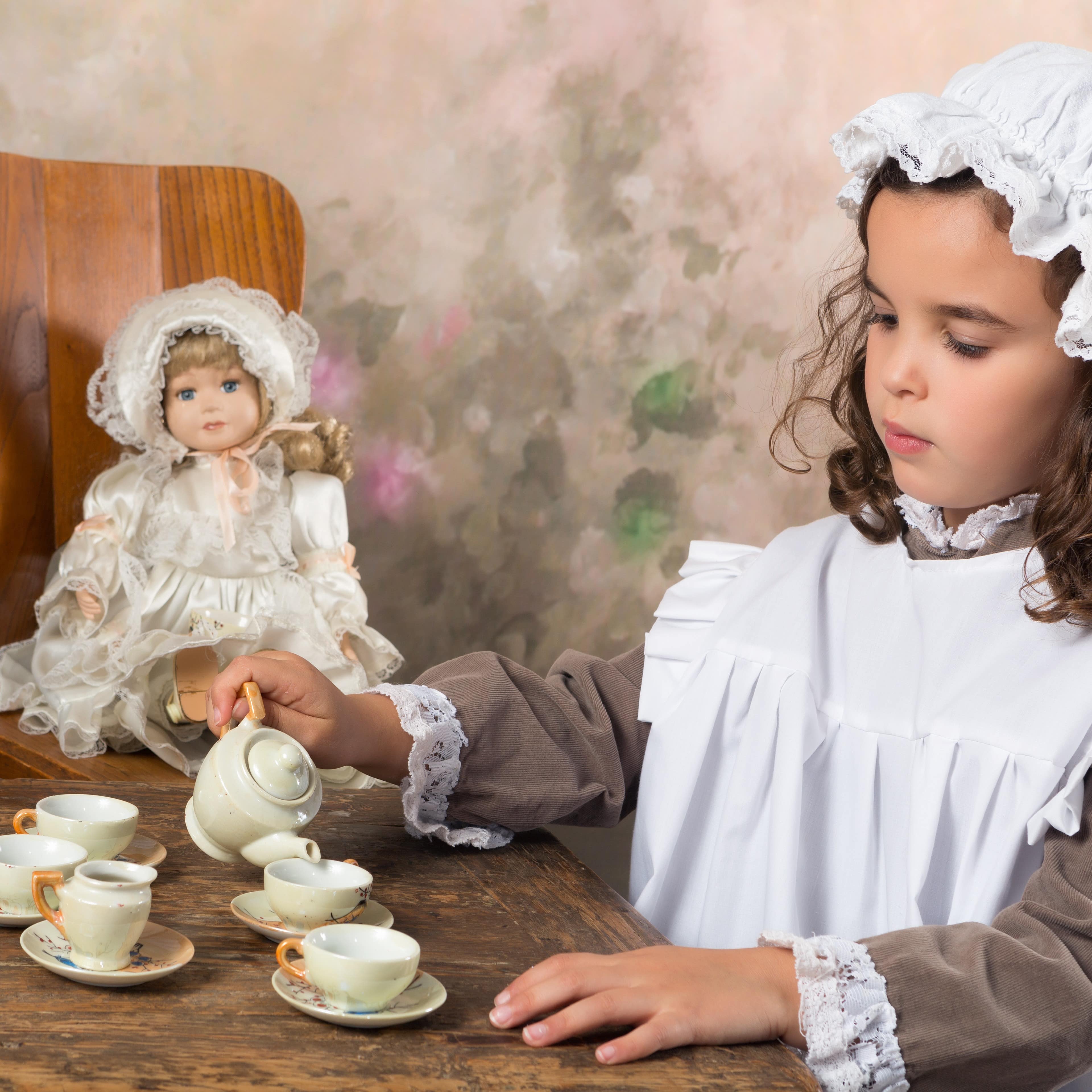 Girl having a vintage tea party with doll