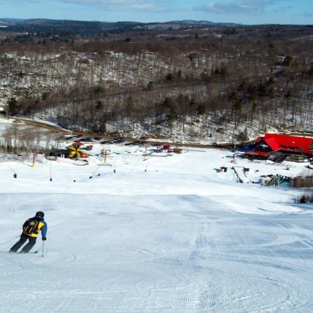 Skier skiing down the slope with surrounding mountains in Mont Cascades Ski Resort