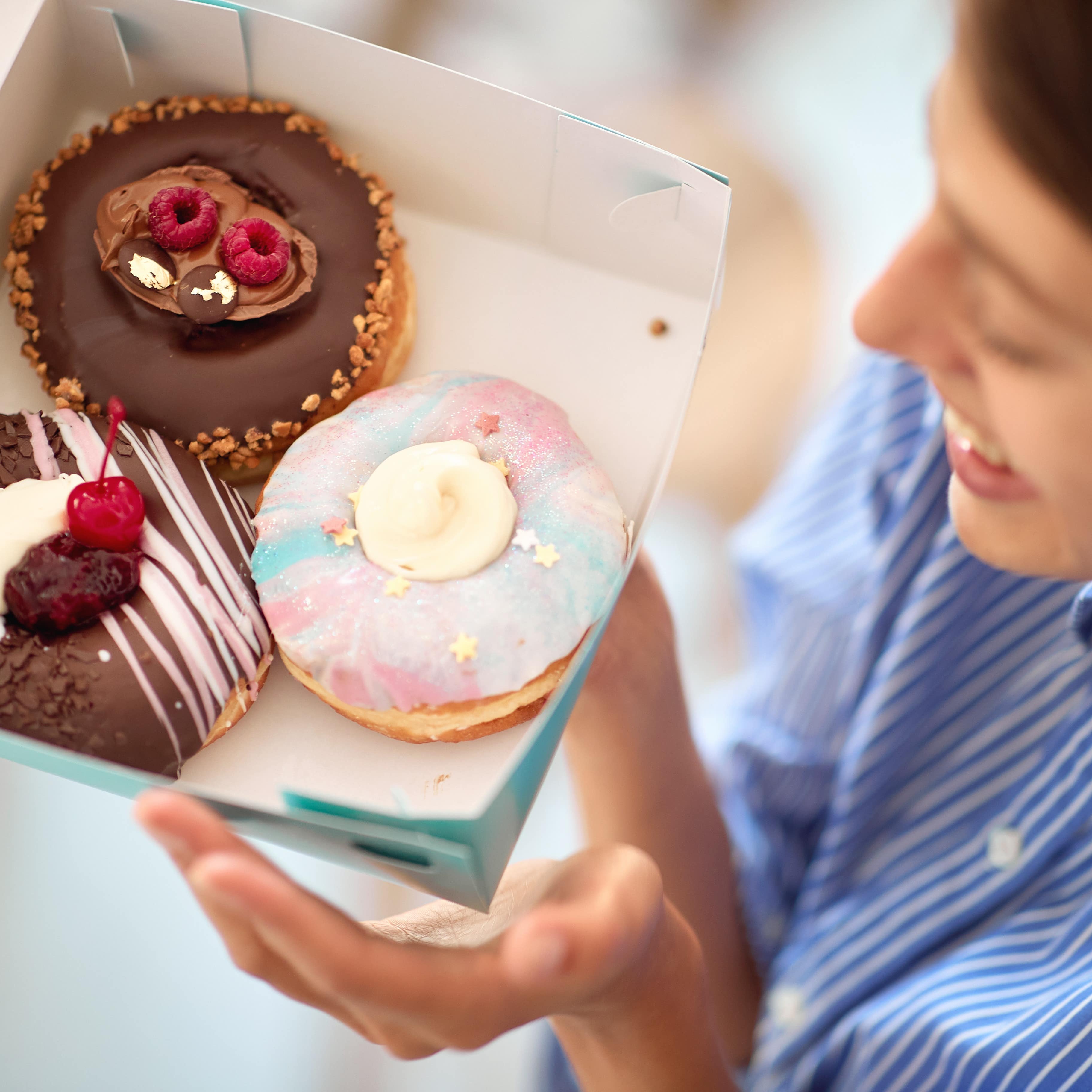 Happy lady looking at a box of fresh donuts