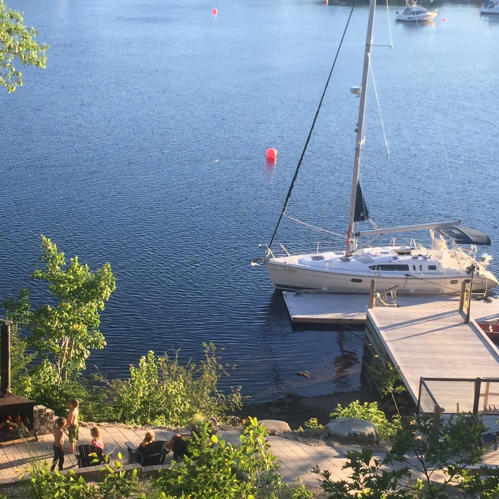 View of a dock with a boat in the water and patio area with a fire pit. 