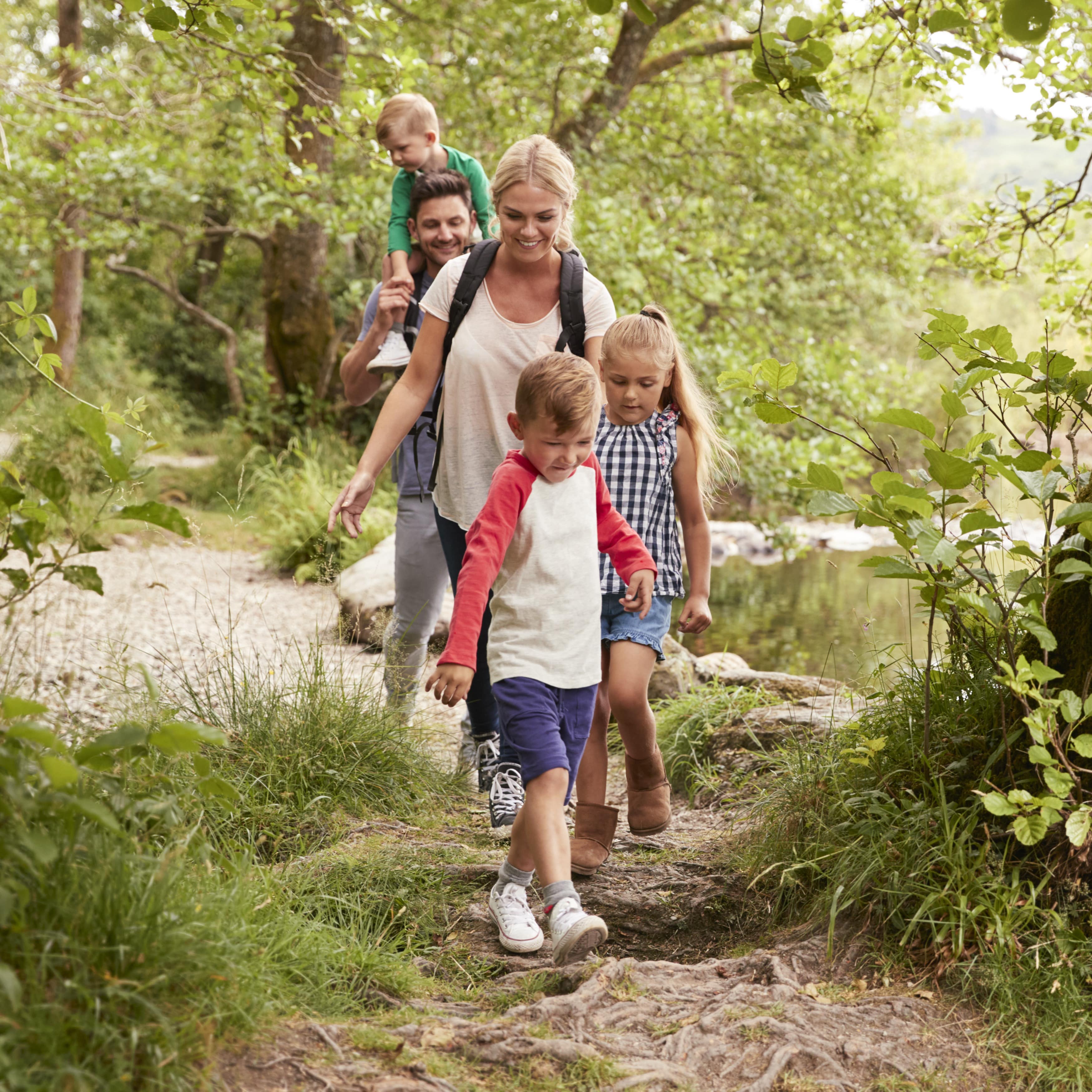 Family hiking on trail beside of a lake