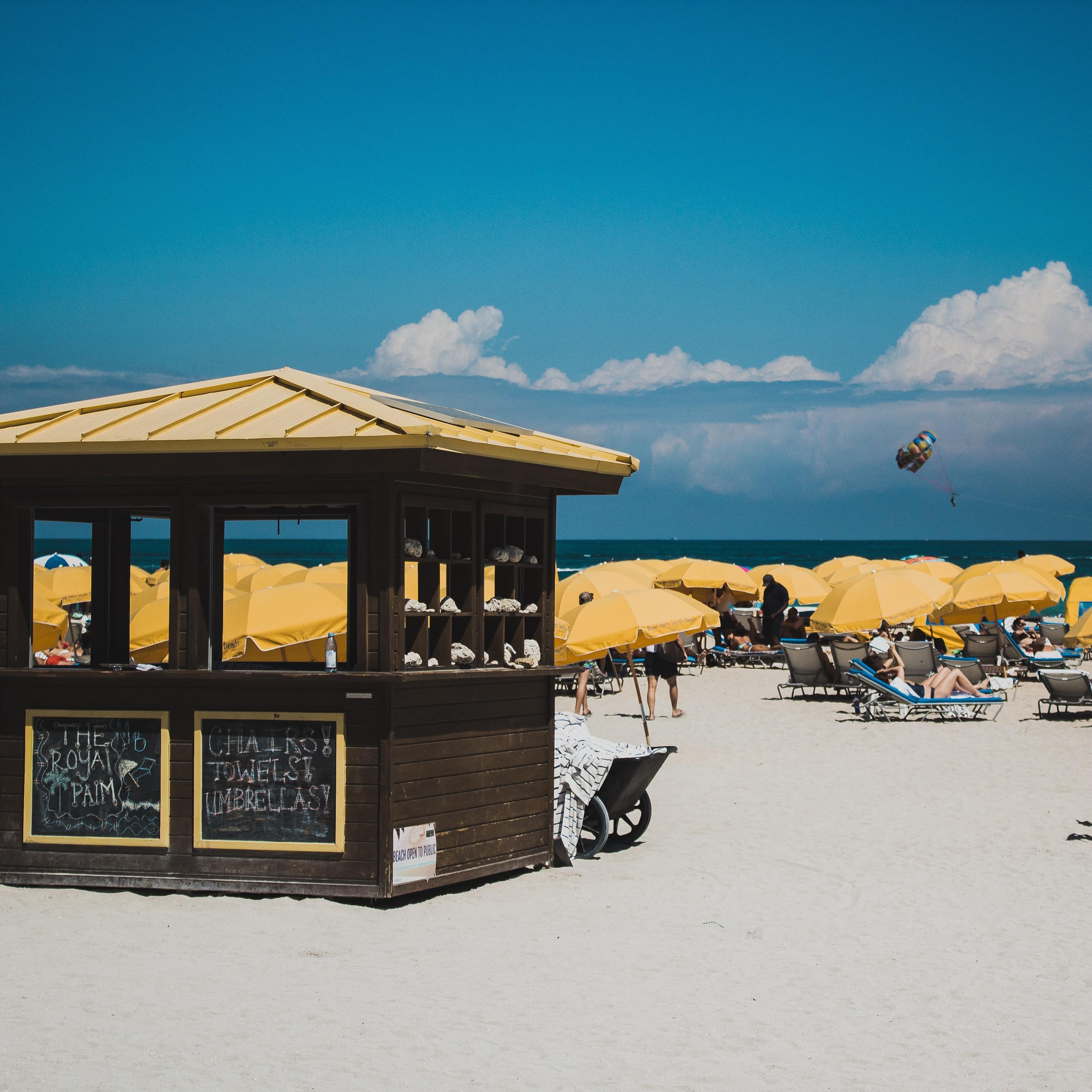 Beachgoers relaxing on the beach in yellow umbrella covered chairs