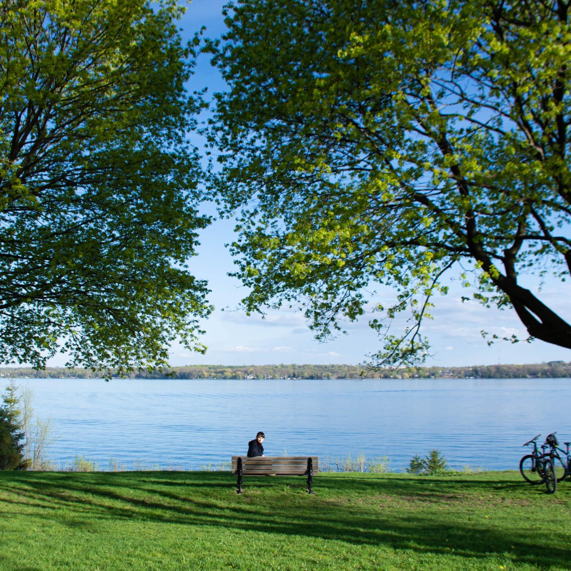 Person sitting on a bench looking at a lake