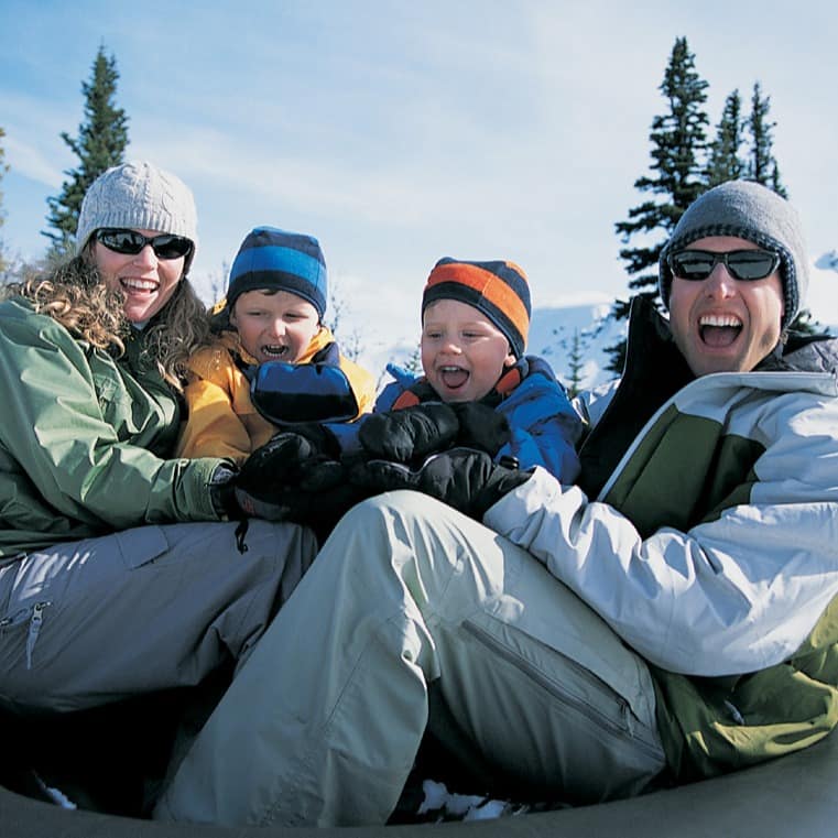 Family of 4 on a snow tube posing for the picture