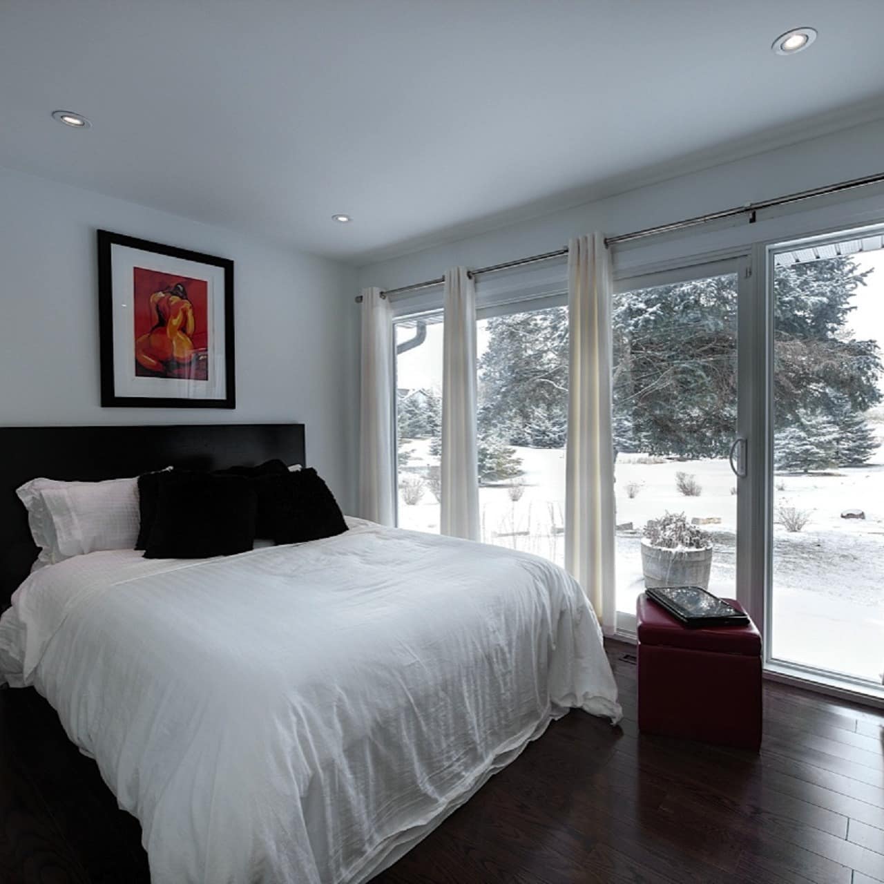 Bedroom with king size bed, black and white decor, and sliding glass doors with views of a snowy rural landscape. 