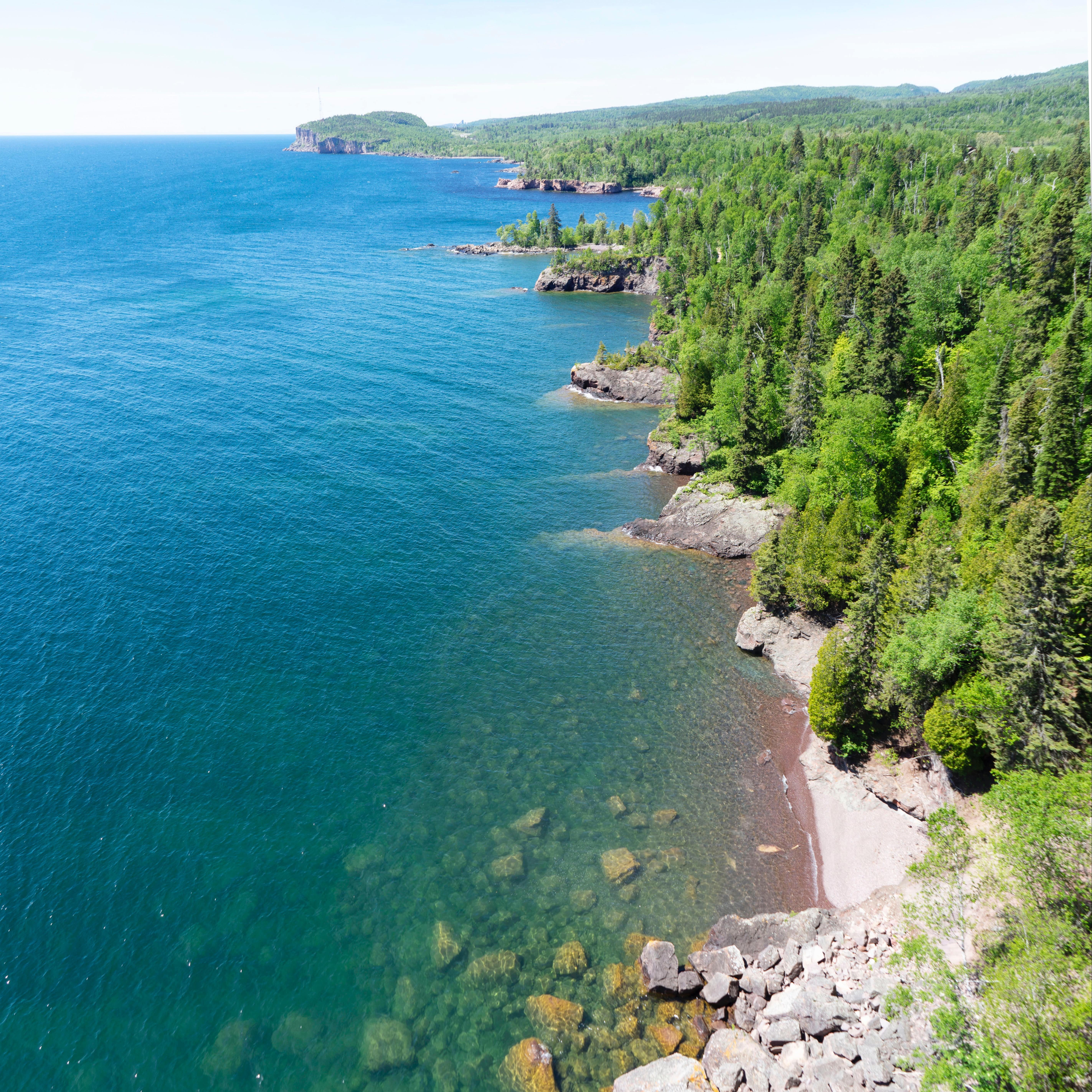 Tree-lined shore against the bright blue waters of Lake Superior