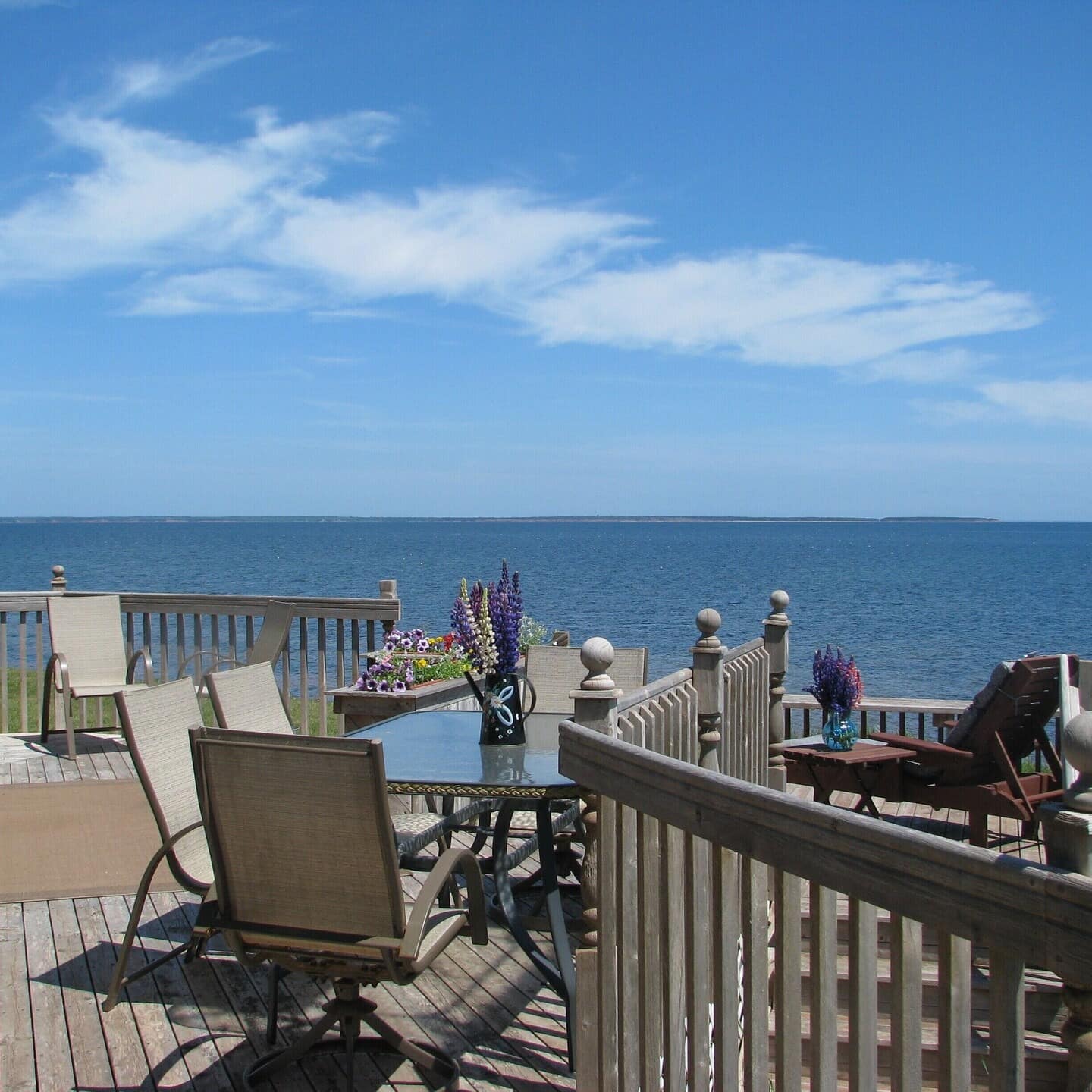 Back deck of a oceanfront beach house on Prince Edward Island decorated with various flowers and chairs