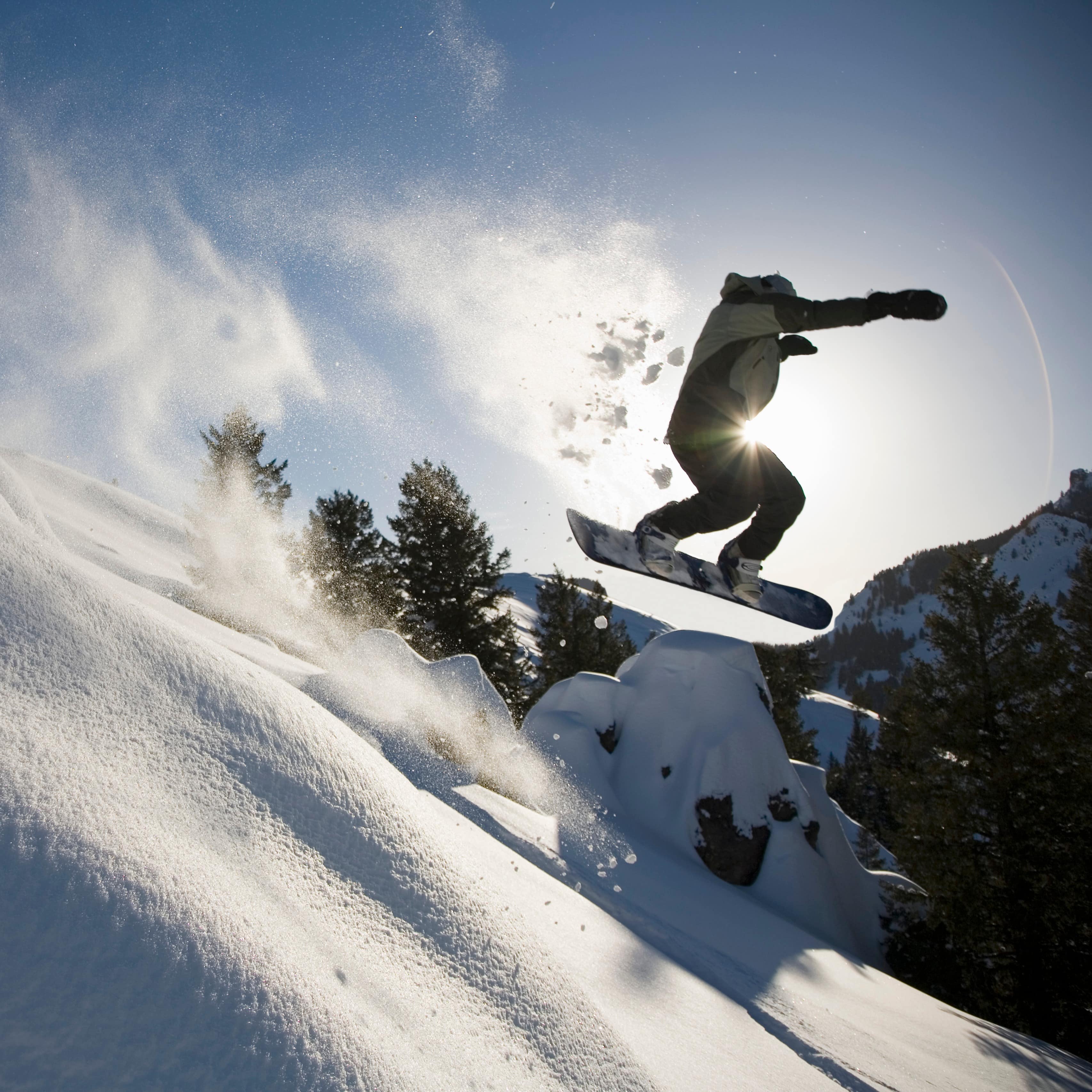 Snowboarder jumping off snowy ledge