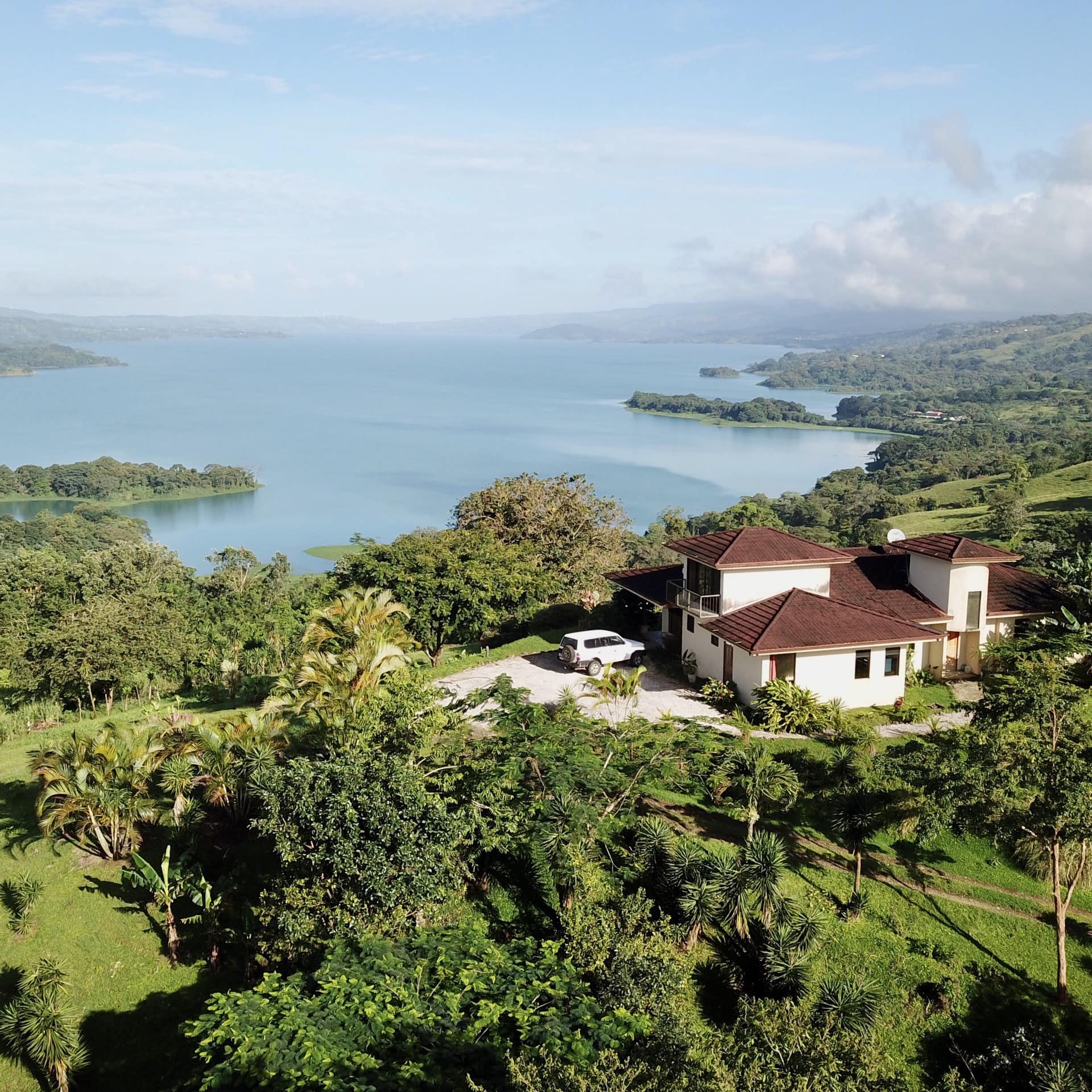 A house sits on the verdant slopes around Lake Arenal