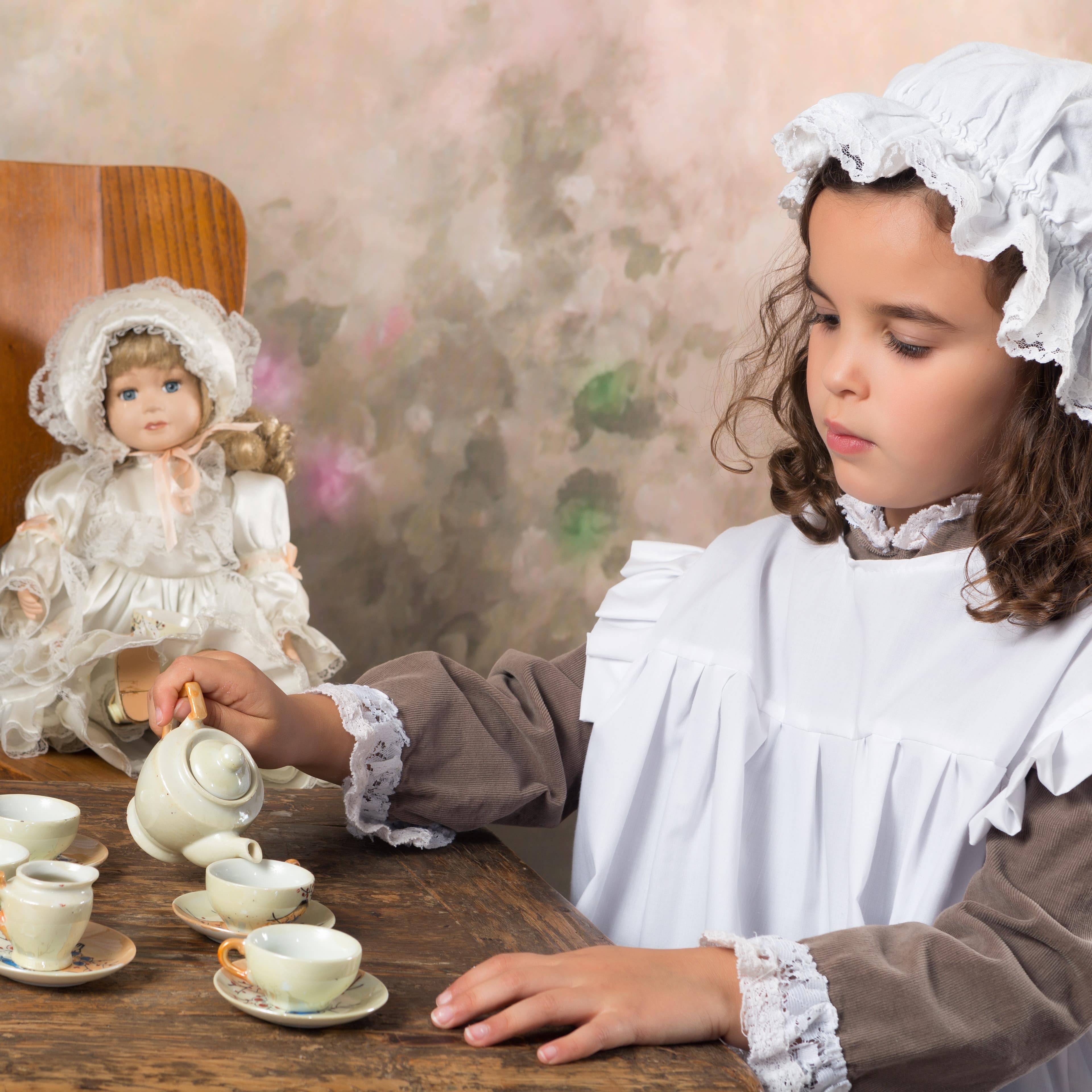 Little girl dressed in vintage clothing having a tea party