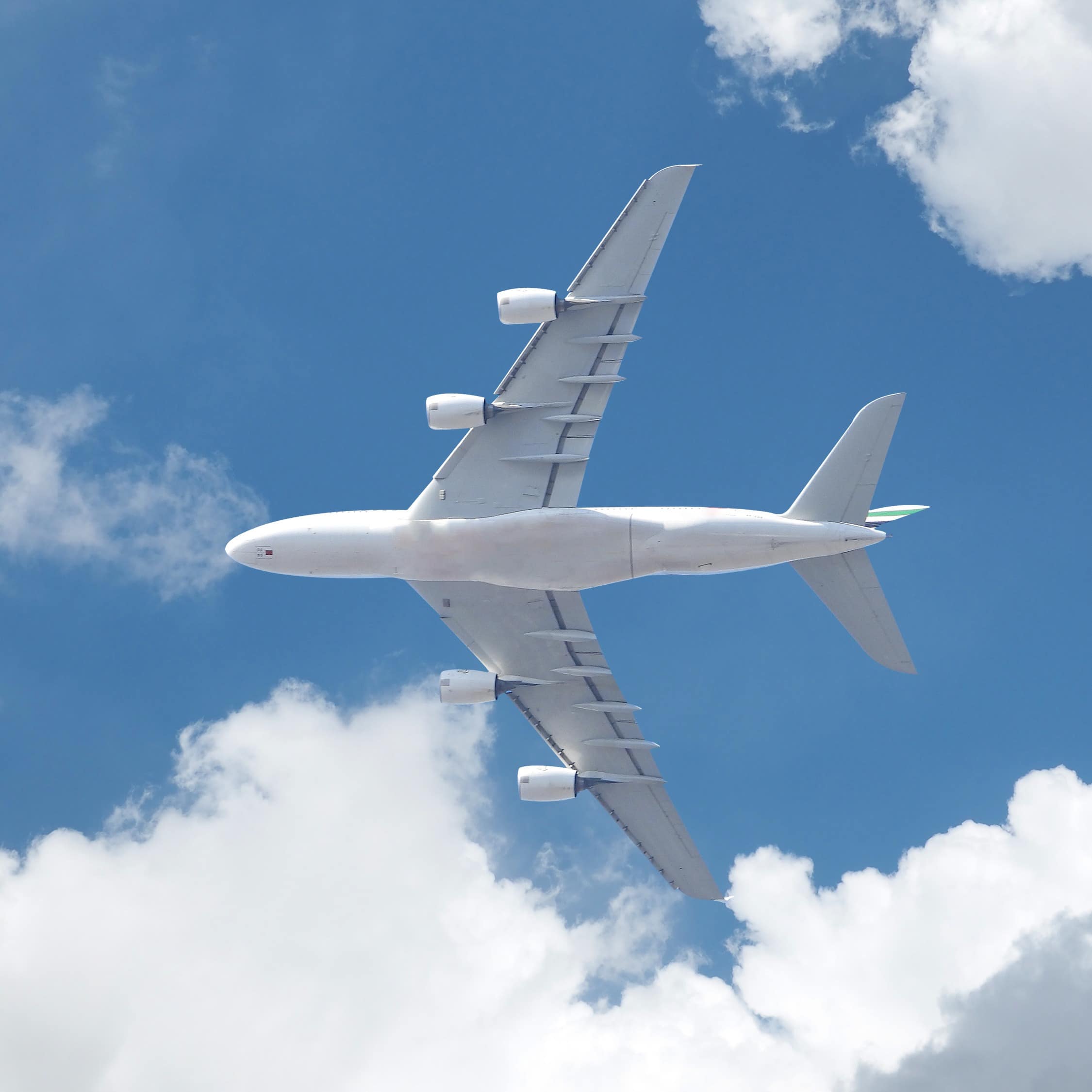 Passenger commercial airplane flying above, as shot from the ground in a cloudy blue sky