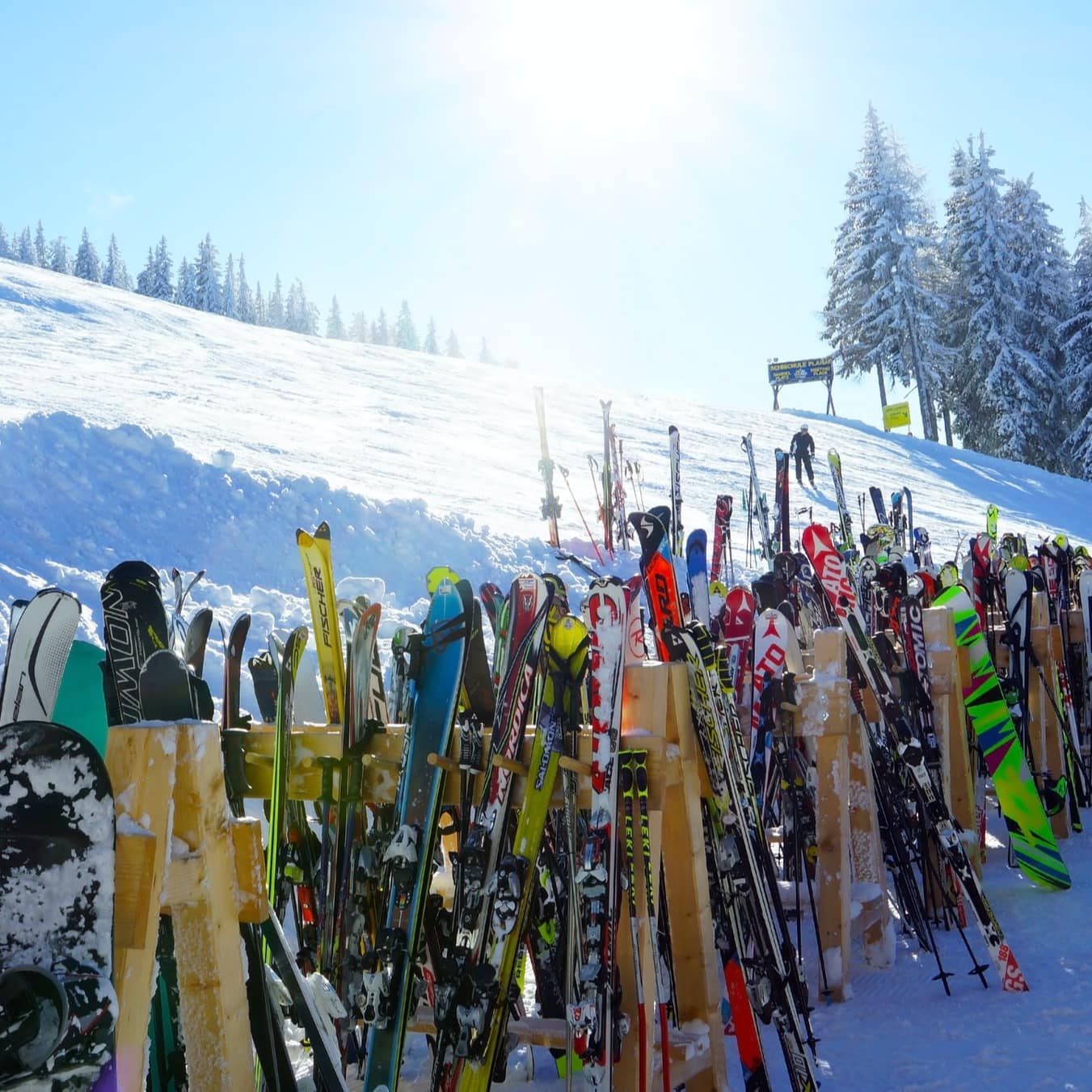 Skis lined up at the foot of a slope on a sunny day 