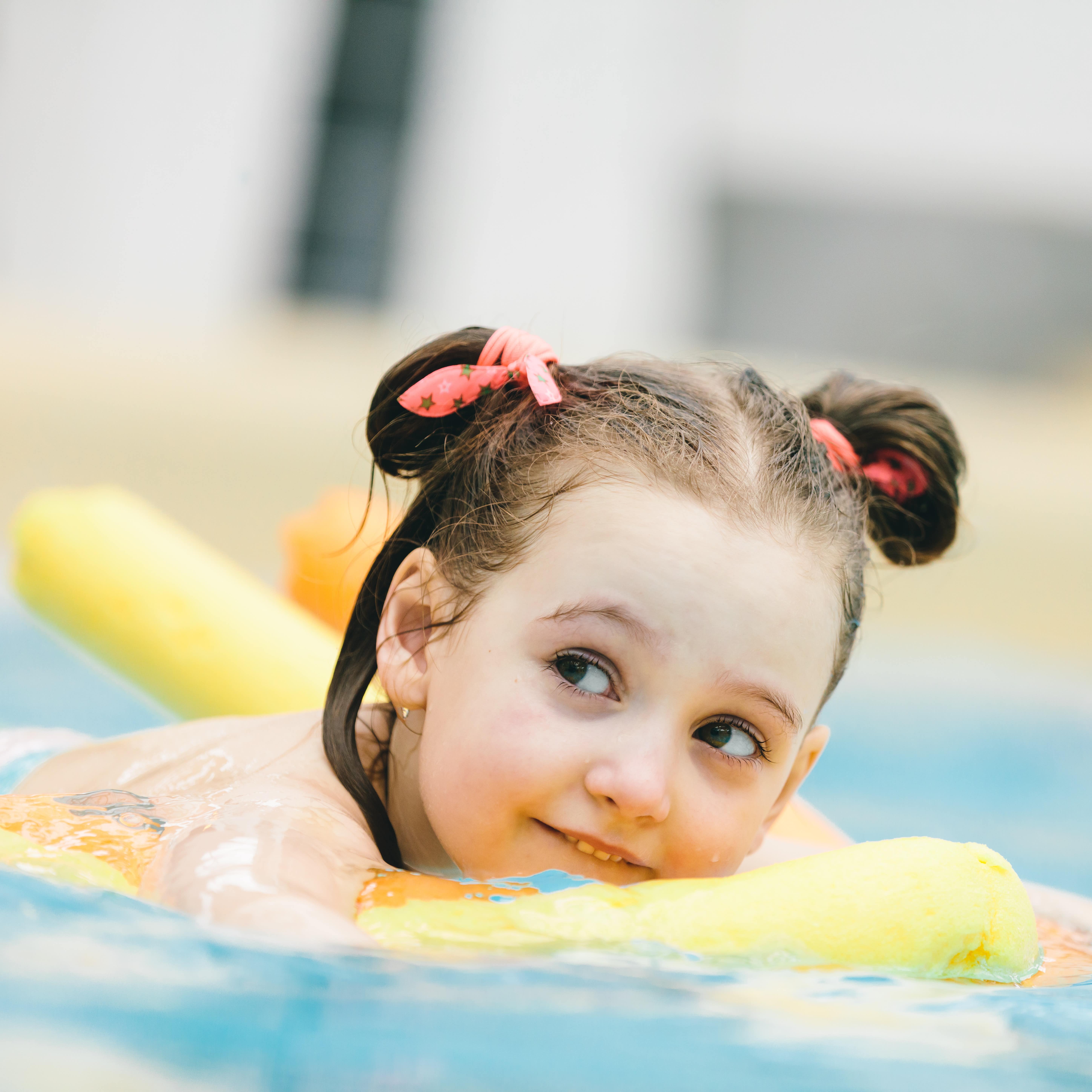 Young girl on a noodle in an indoor pool