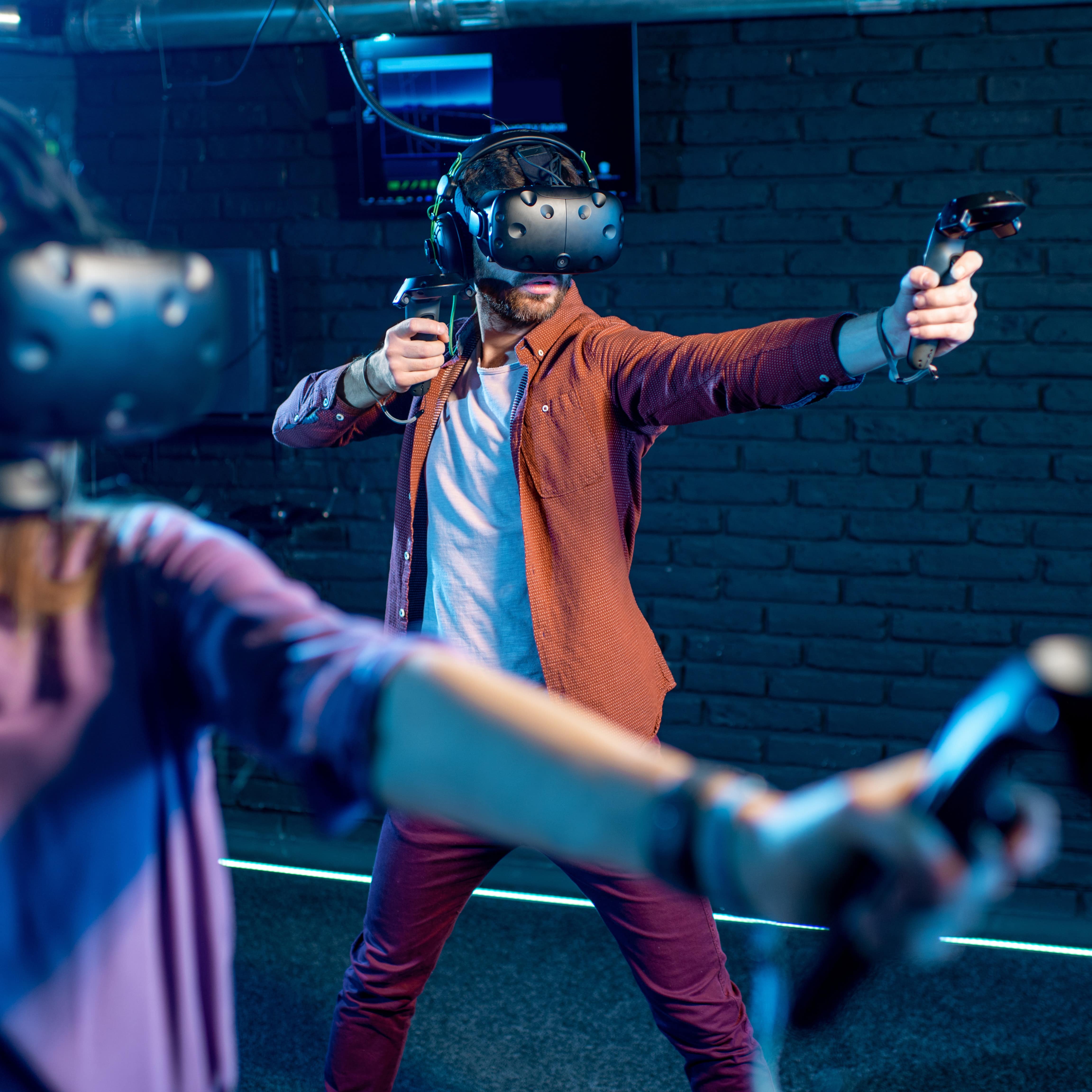 Man and woman playing game using virtual reality headset and gamepads