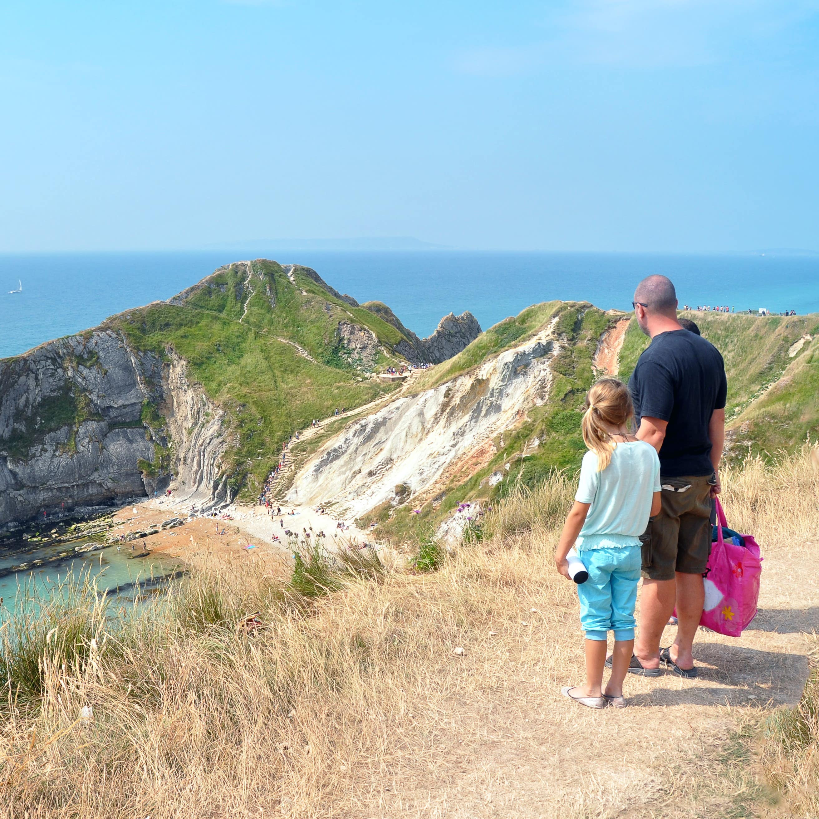 Father and daughter standing on the hill above the Jurassic Coast