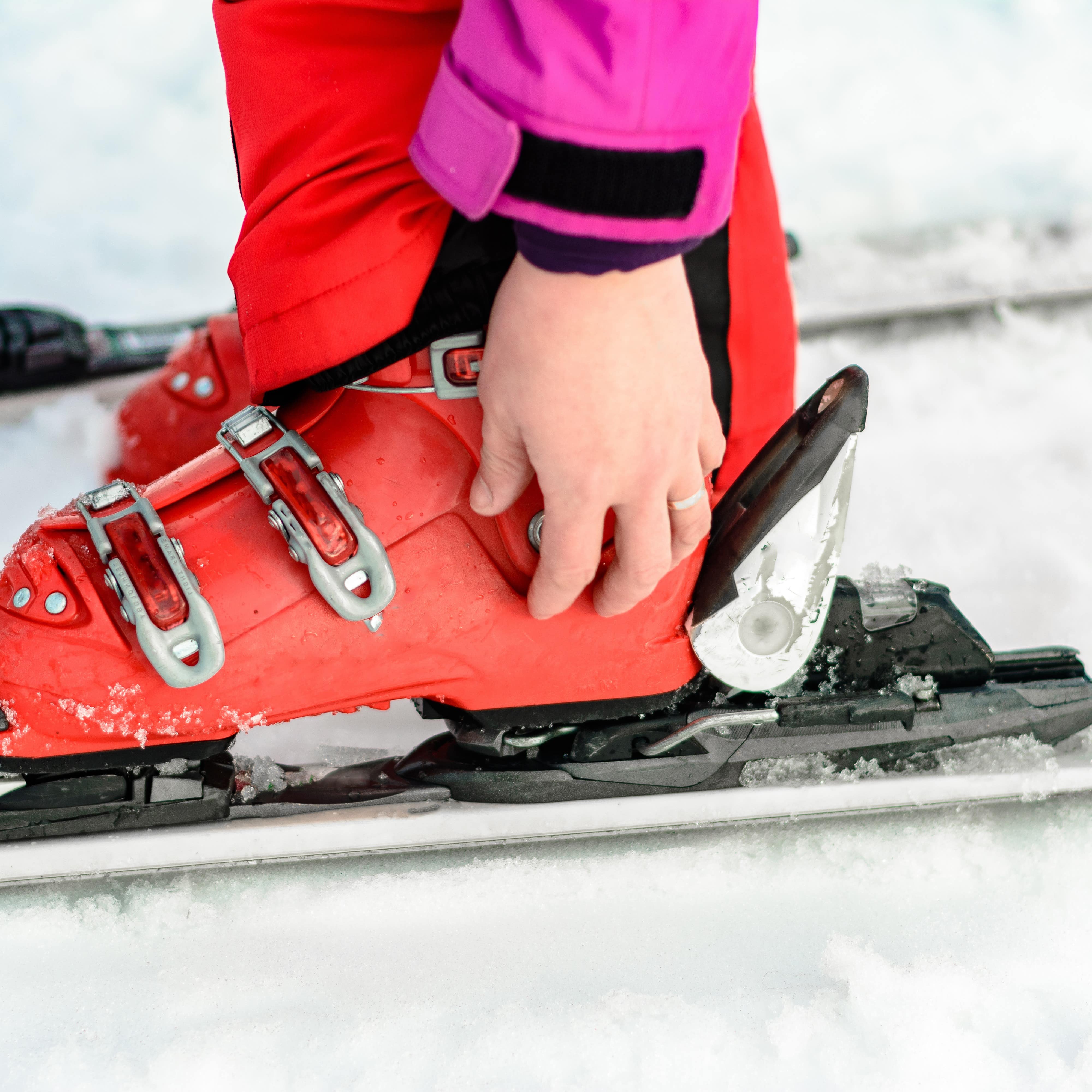 Close up of person clipping ski boots onto ski