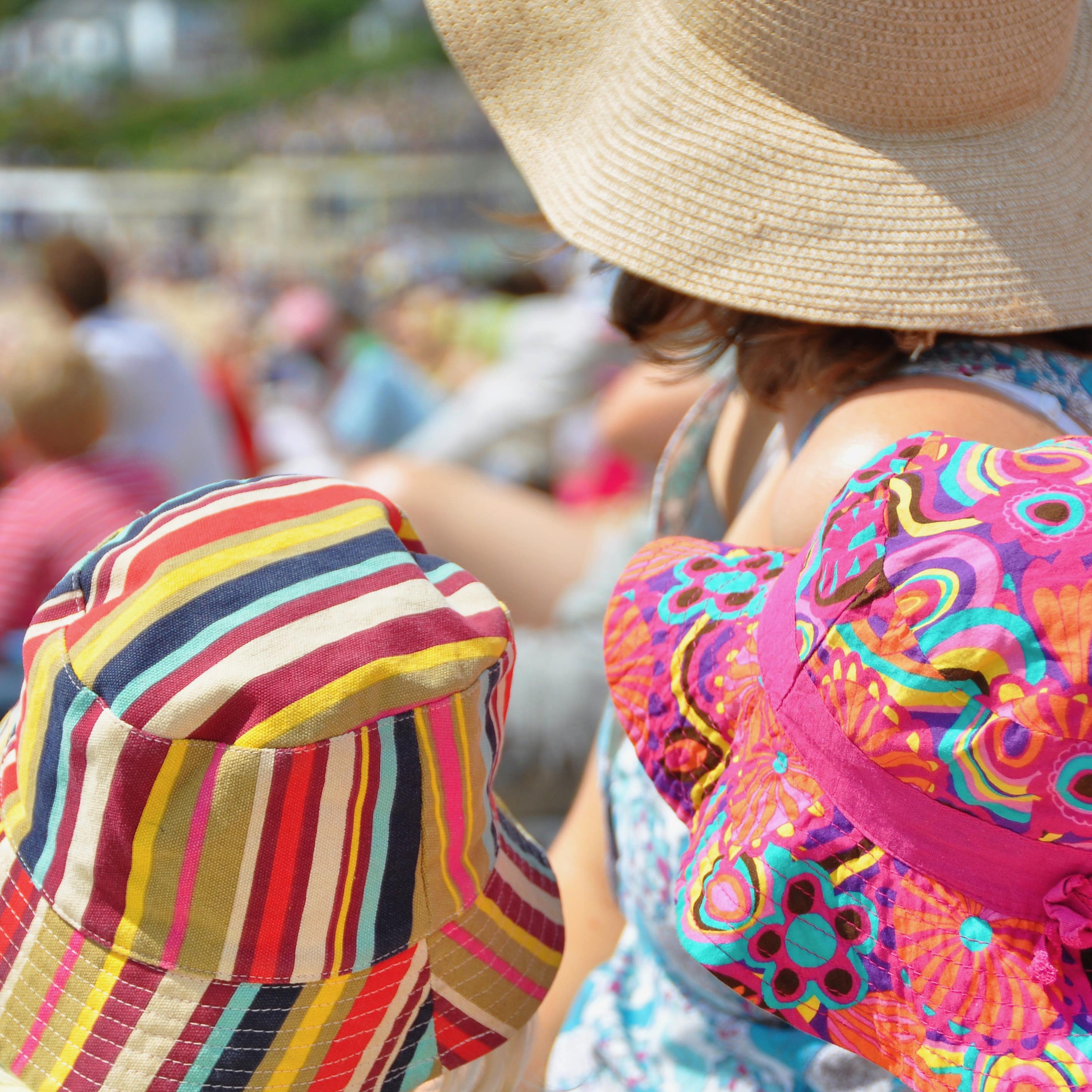 Colourful beach hats on 2 children and their mother on Dorset Beach