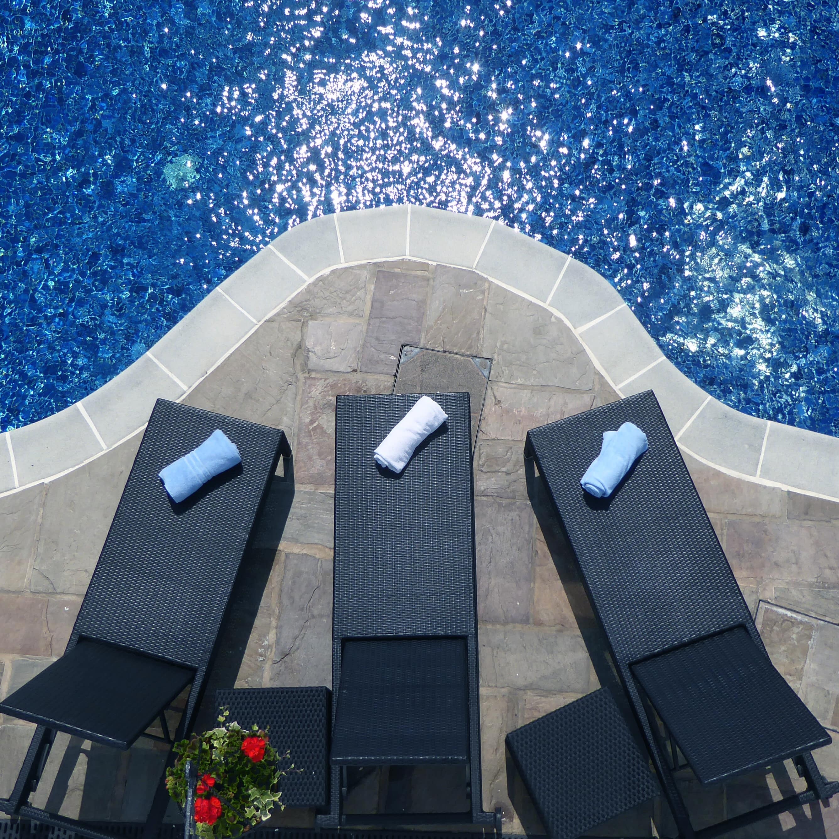 Aeriel view of 3 pool loungers sitting next to a sparkling blue pool