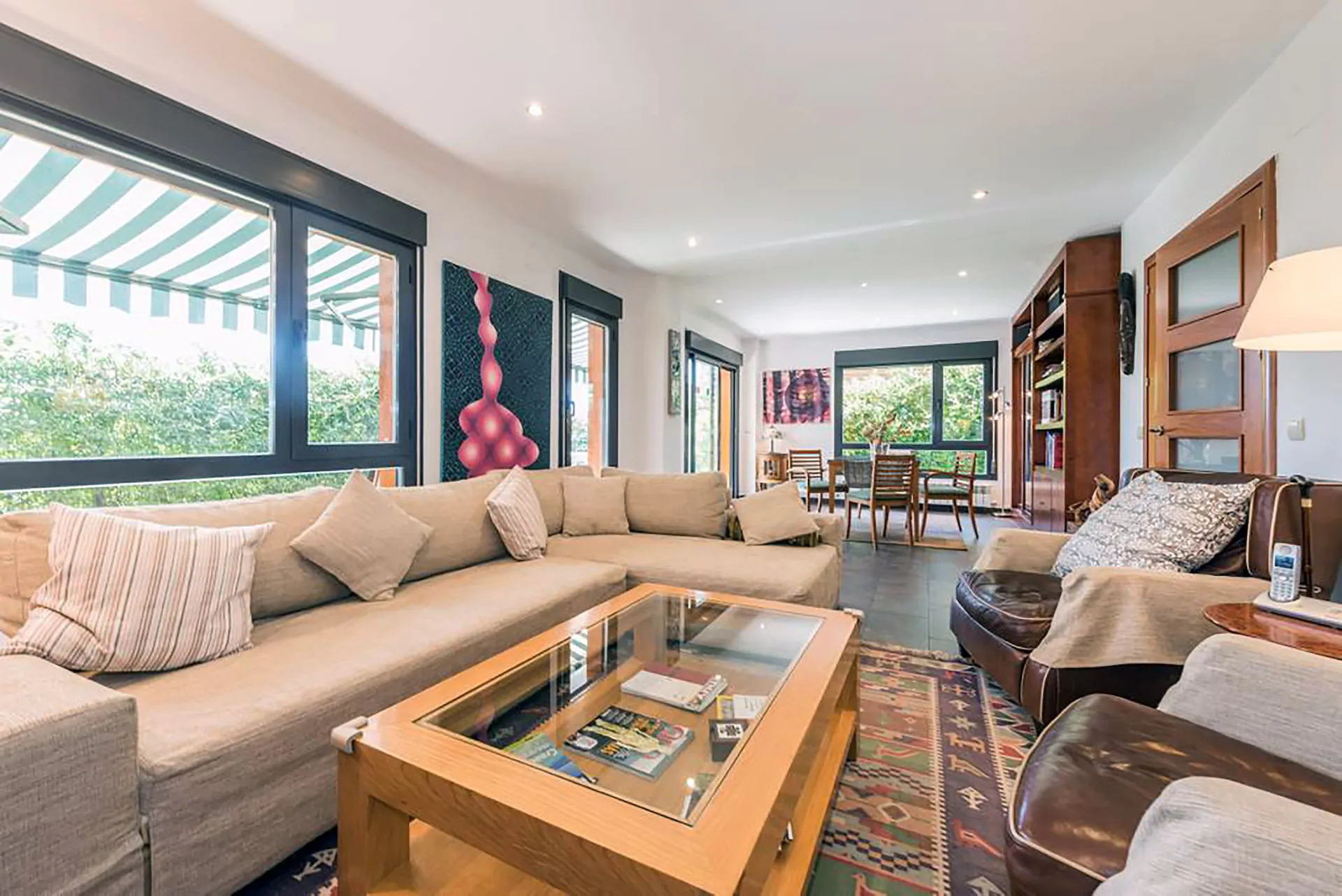 Gran estancia con zona de sofá y sillones en primer plano y comedor al fondo