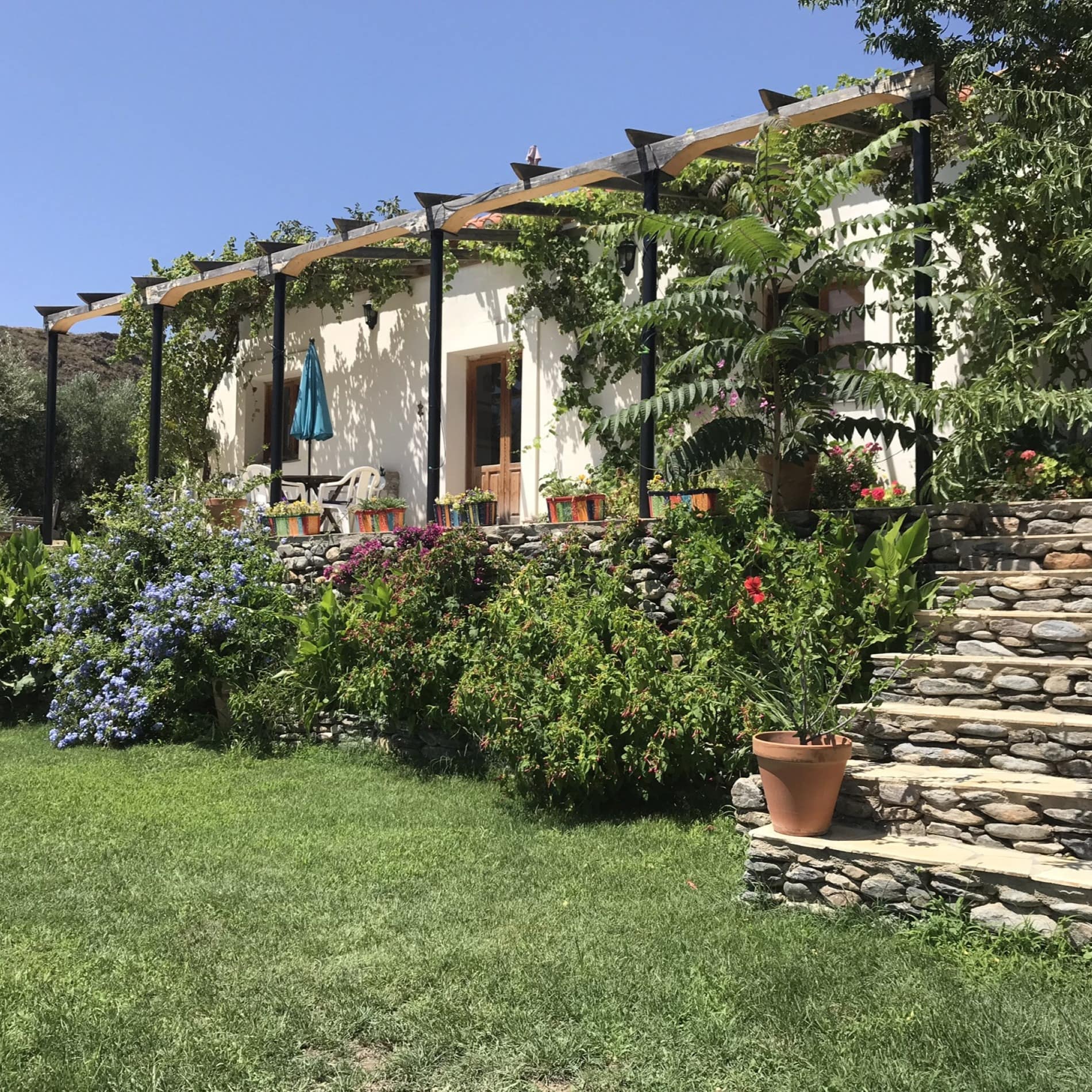 Casa de campo blanca con escaleras de piedra para subir al porche y decorada con grandes macetas