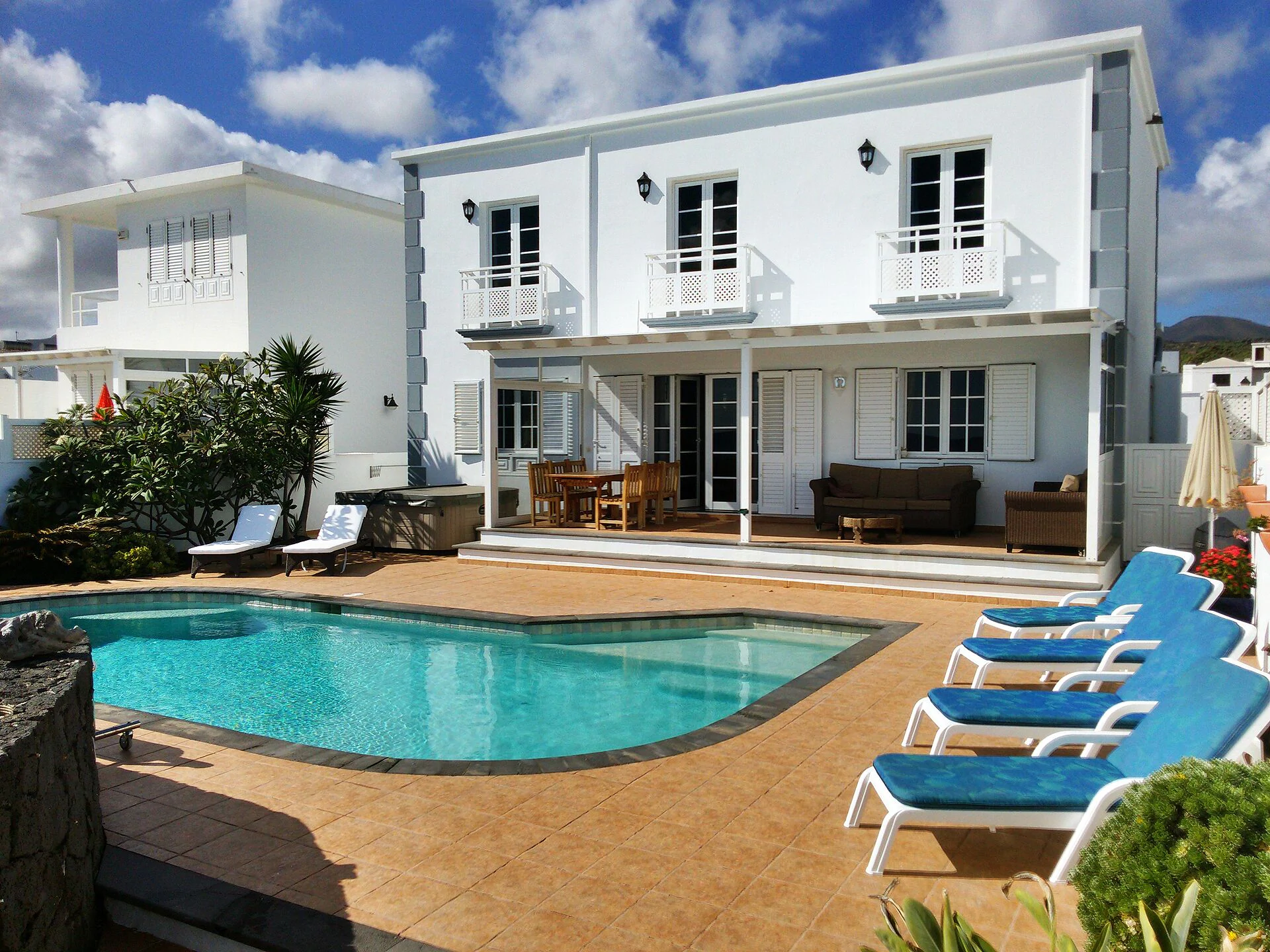 Villa de dos plantas en tonos blancos con porche, piscina y hamacas