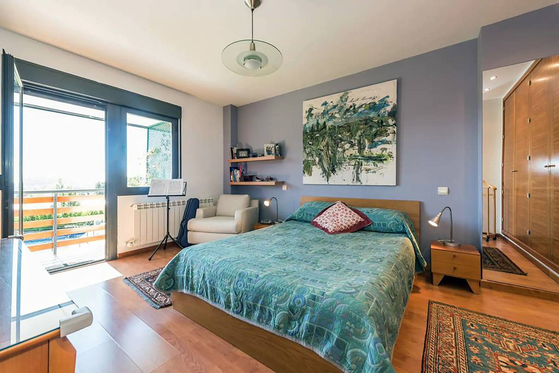 Amplio dormitorio con cama de matrimonio, sillón y gran balcón con vistas