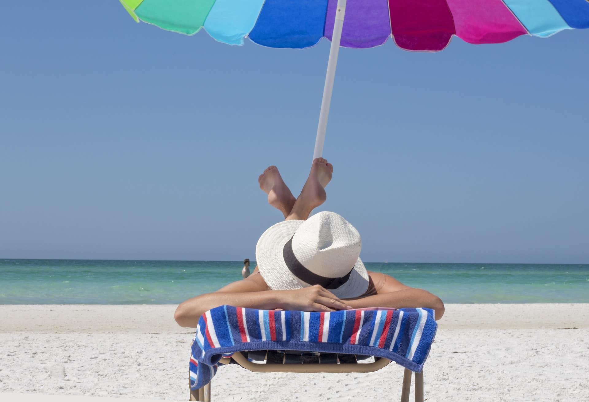 Stock image - Woman on beach holiday summer vacation with umbrella