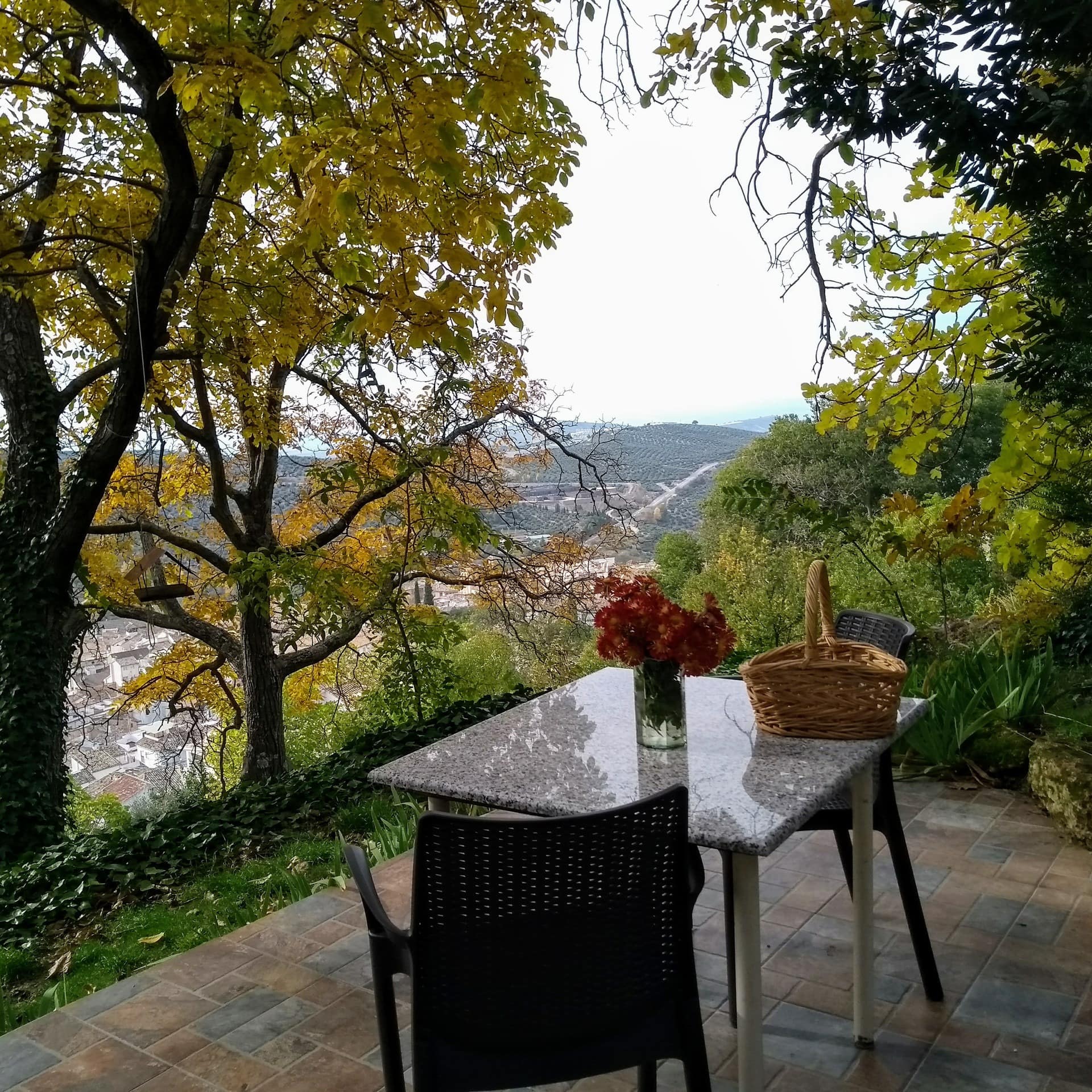 Pequeño mirador con suelo de baldosas y mesa con sillas con vistas a un pueblo blanco y a las montañas