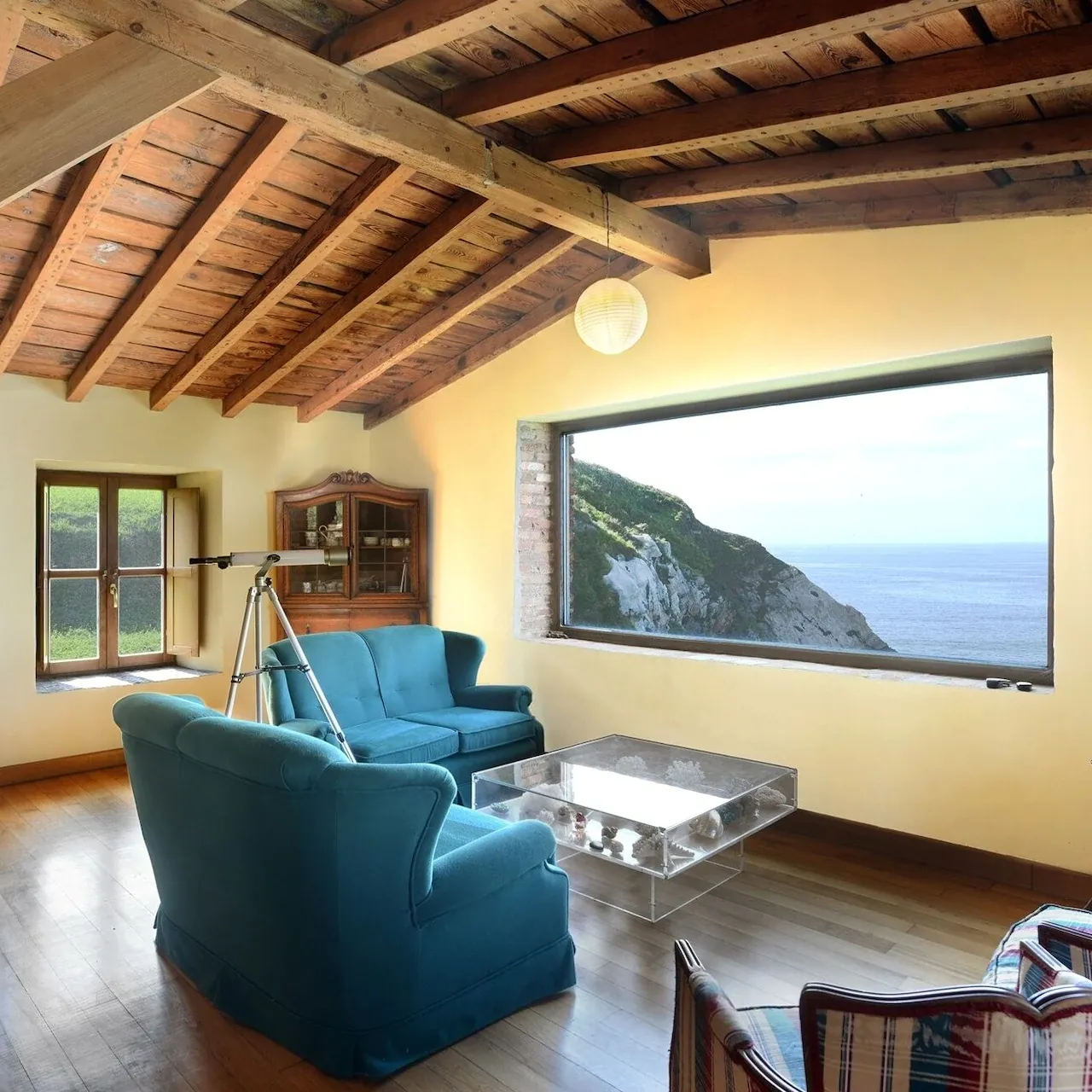 Salón con techo de madera y gran ventana con vistas al mar y los acantilados de Arnao