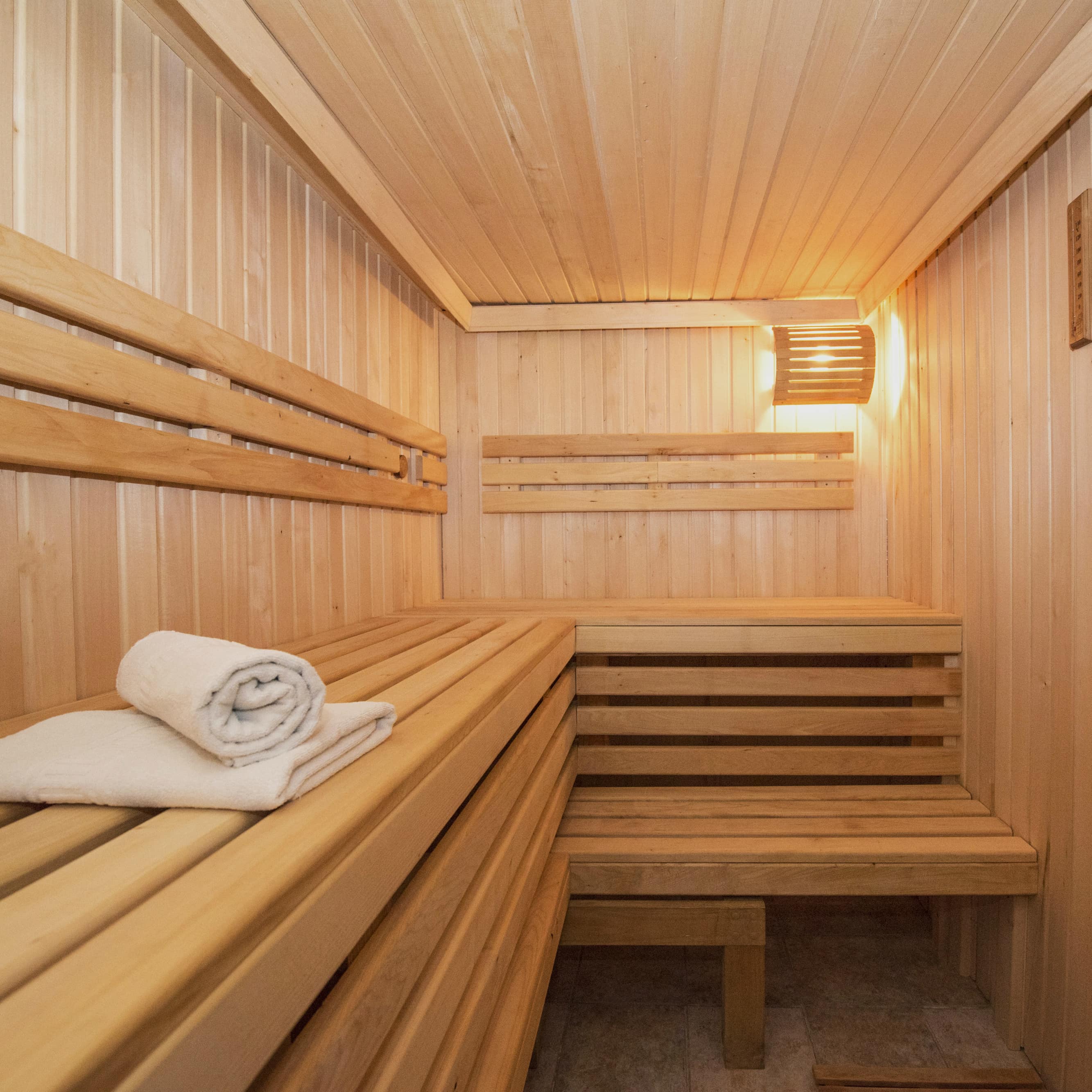 Kleine houten sauna met opgevouwen handdoeken op de bank