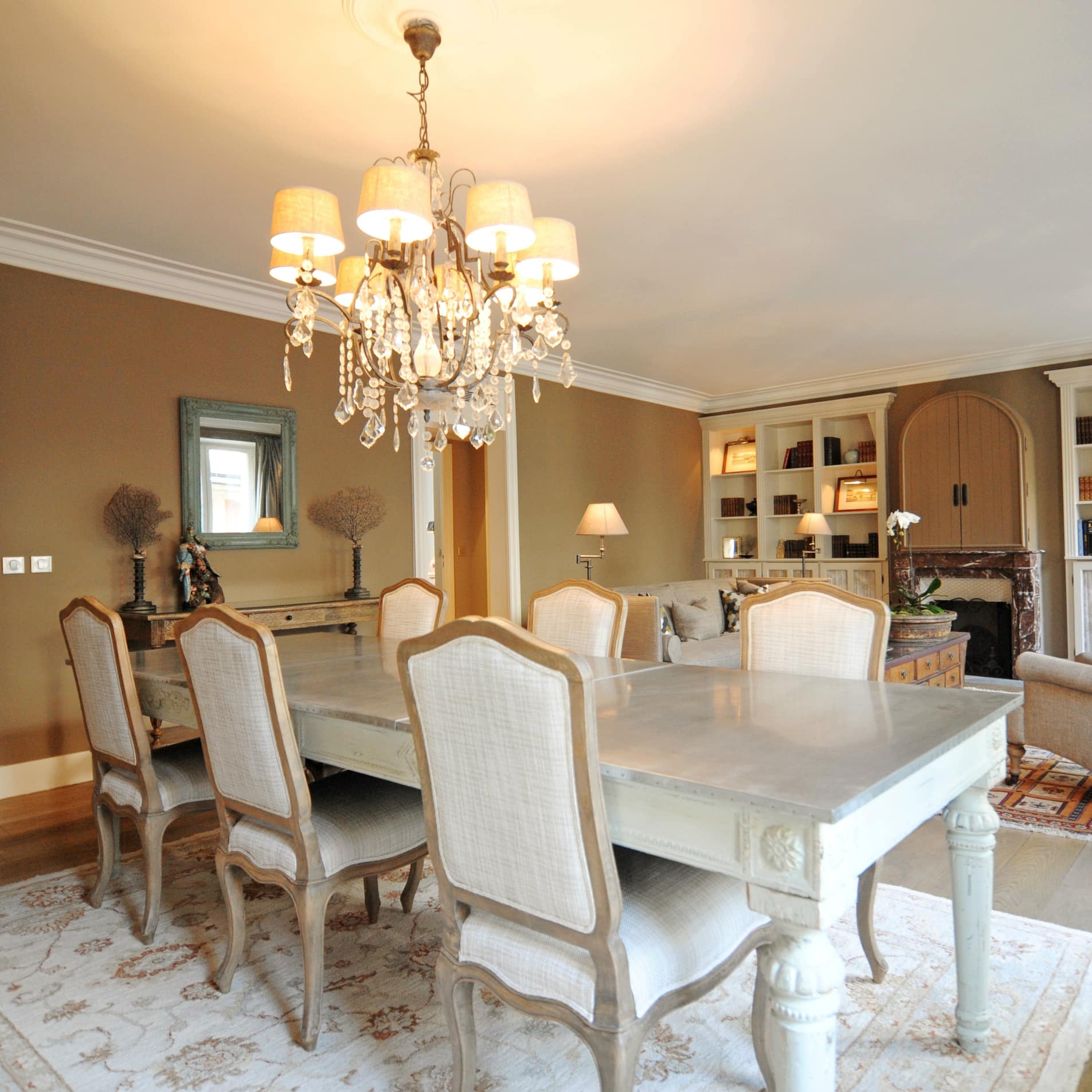 Luxe appartement in klassieke stijl met kroonluchter boven de dinertafel.