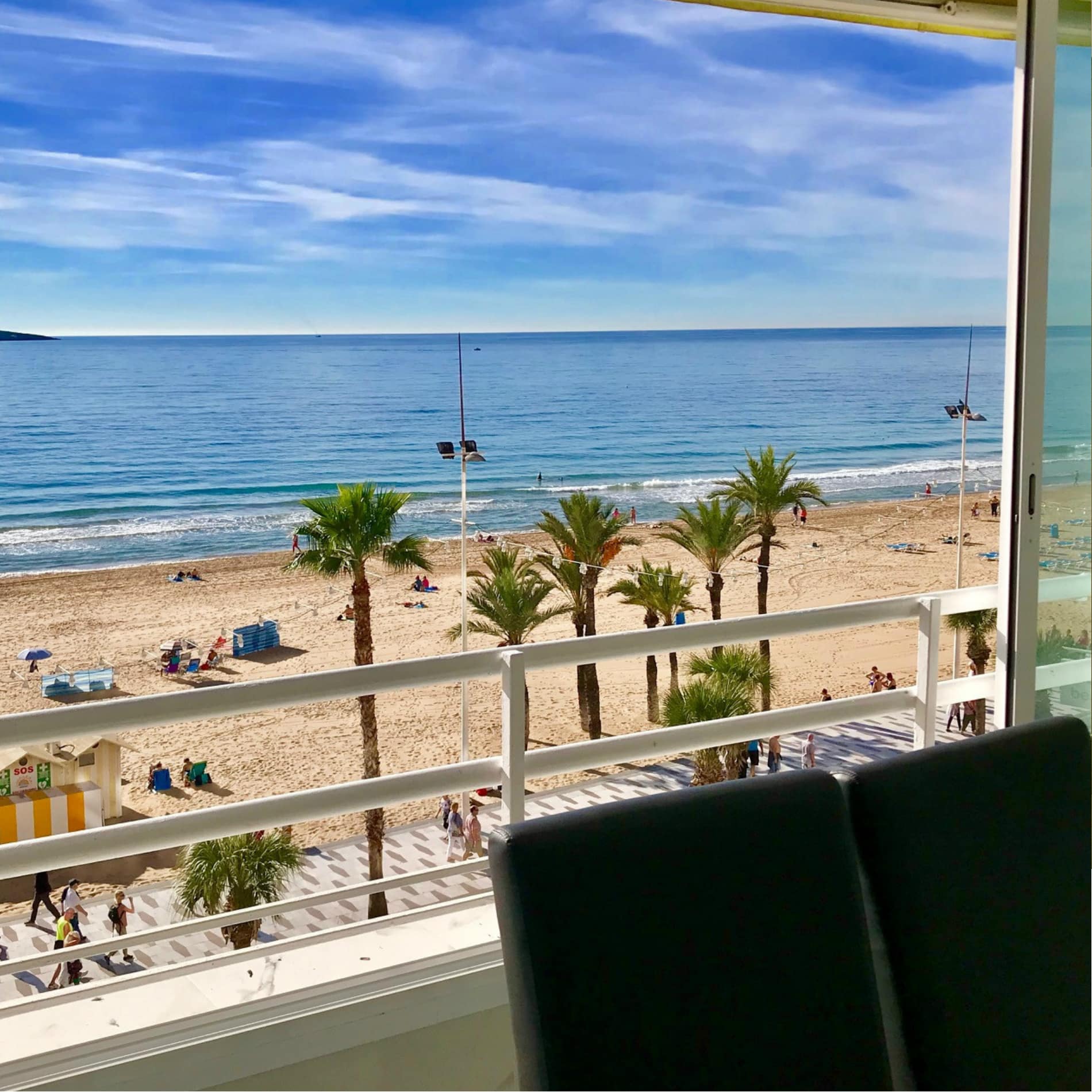 Uitzicht op het strand met palmen en promenade vanaf het balkon van het appartement